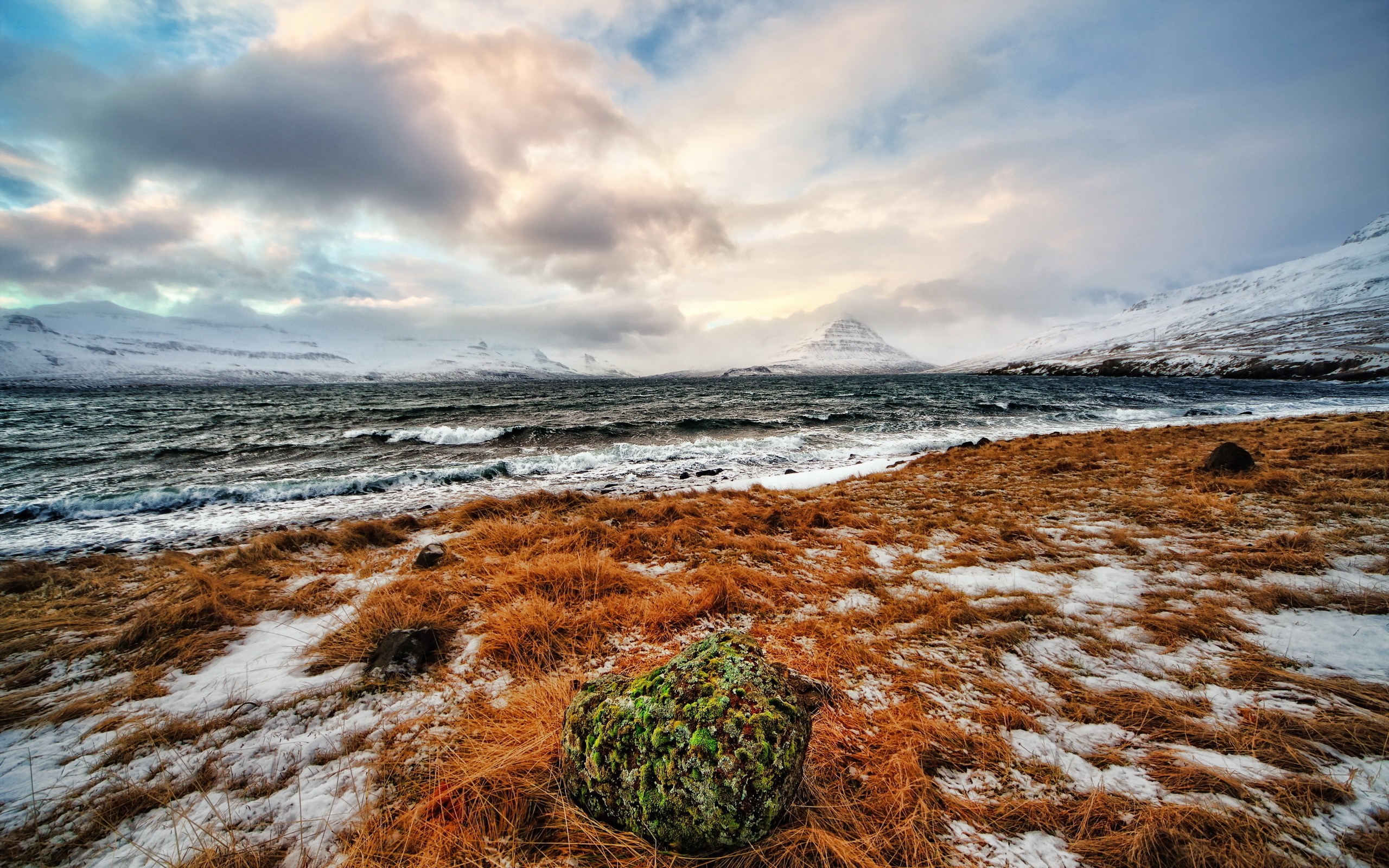 Winter landscape with snow-covered mountains and a rough sea HD Wallpaper