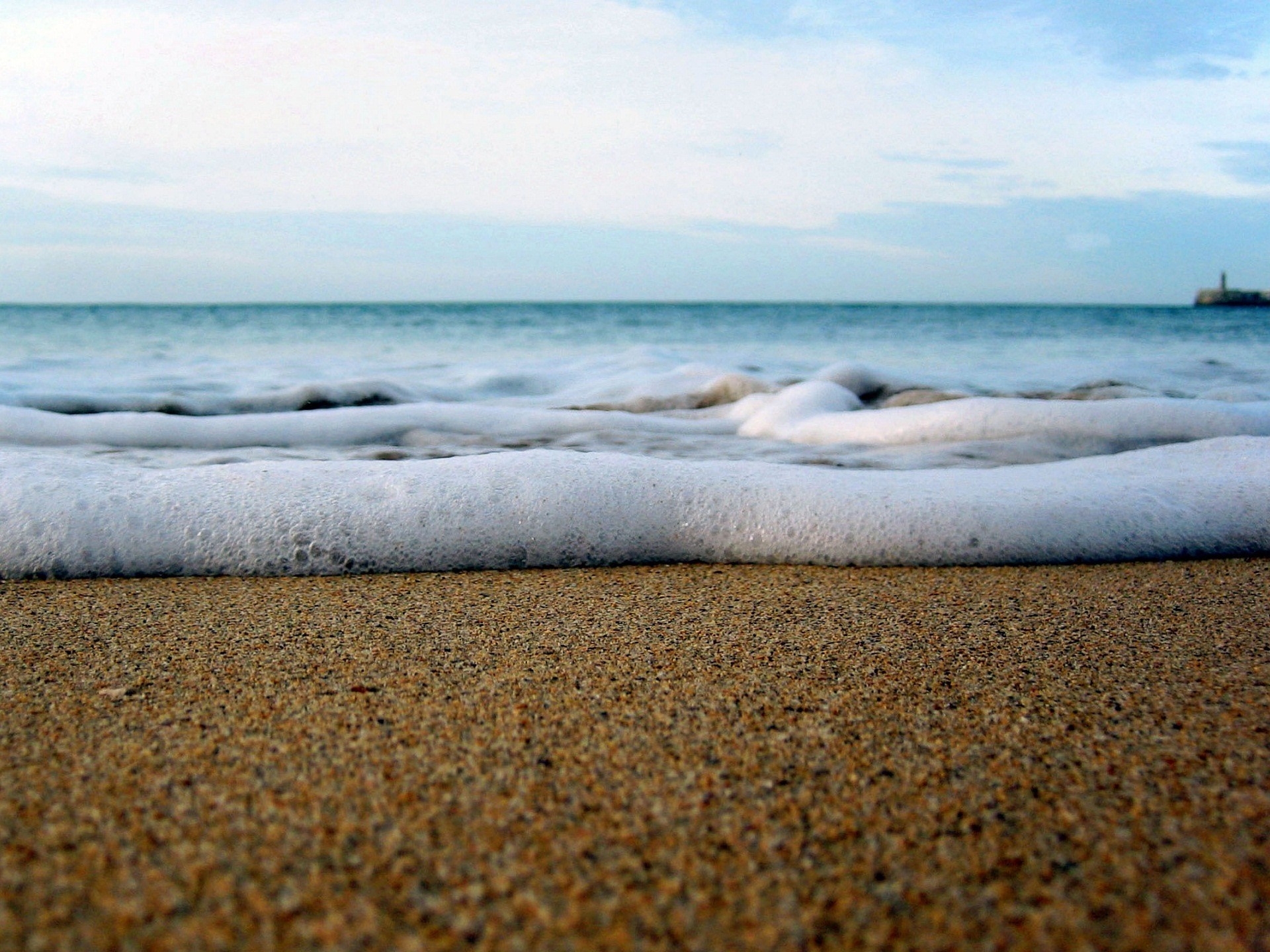 Ocean waves washing onto a sandy beach HD Wallpaper