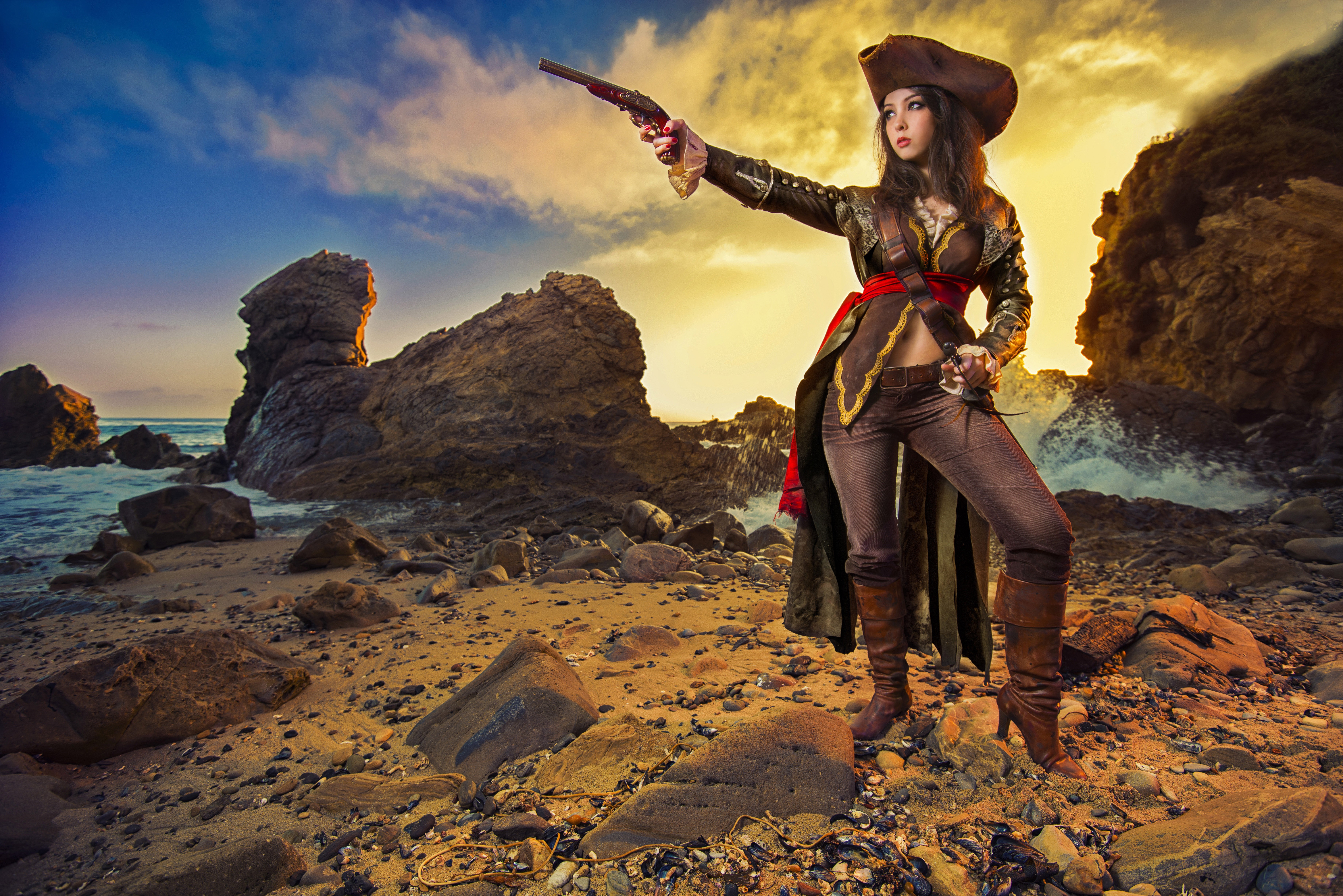 Woman dressed as a pirate holding a pistol on a rocky coast HD Wallpaper