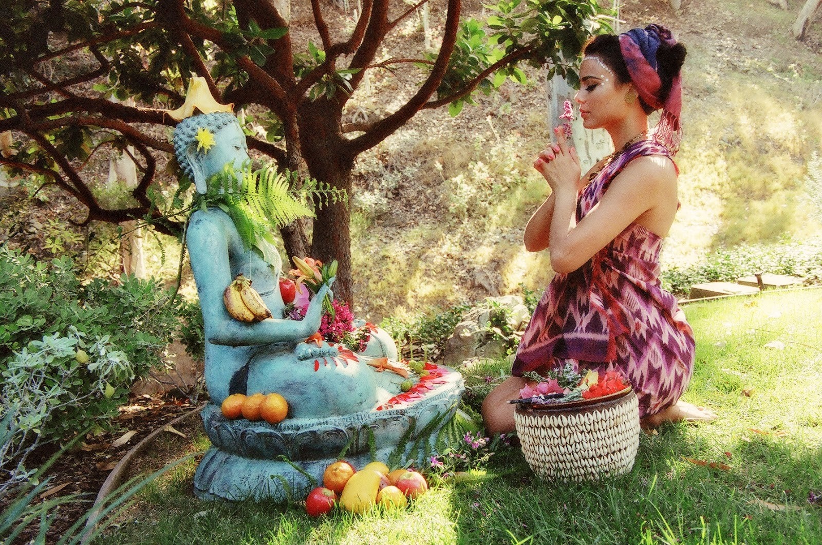 Nathalie Kelley praying in a garden next to a Buddha statue HD Wallpaper