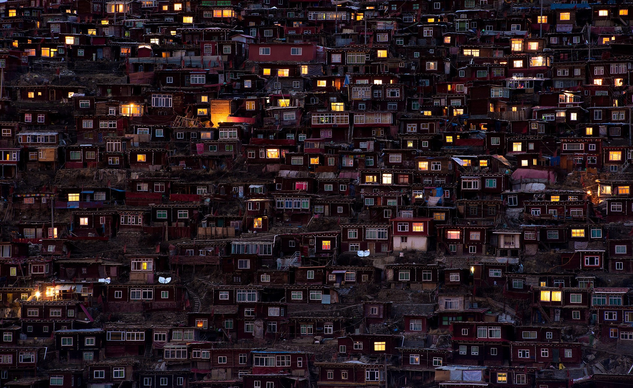 Hillside village with illuminated windows at dusk HD Wallpaper
