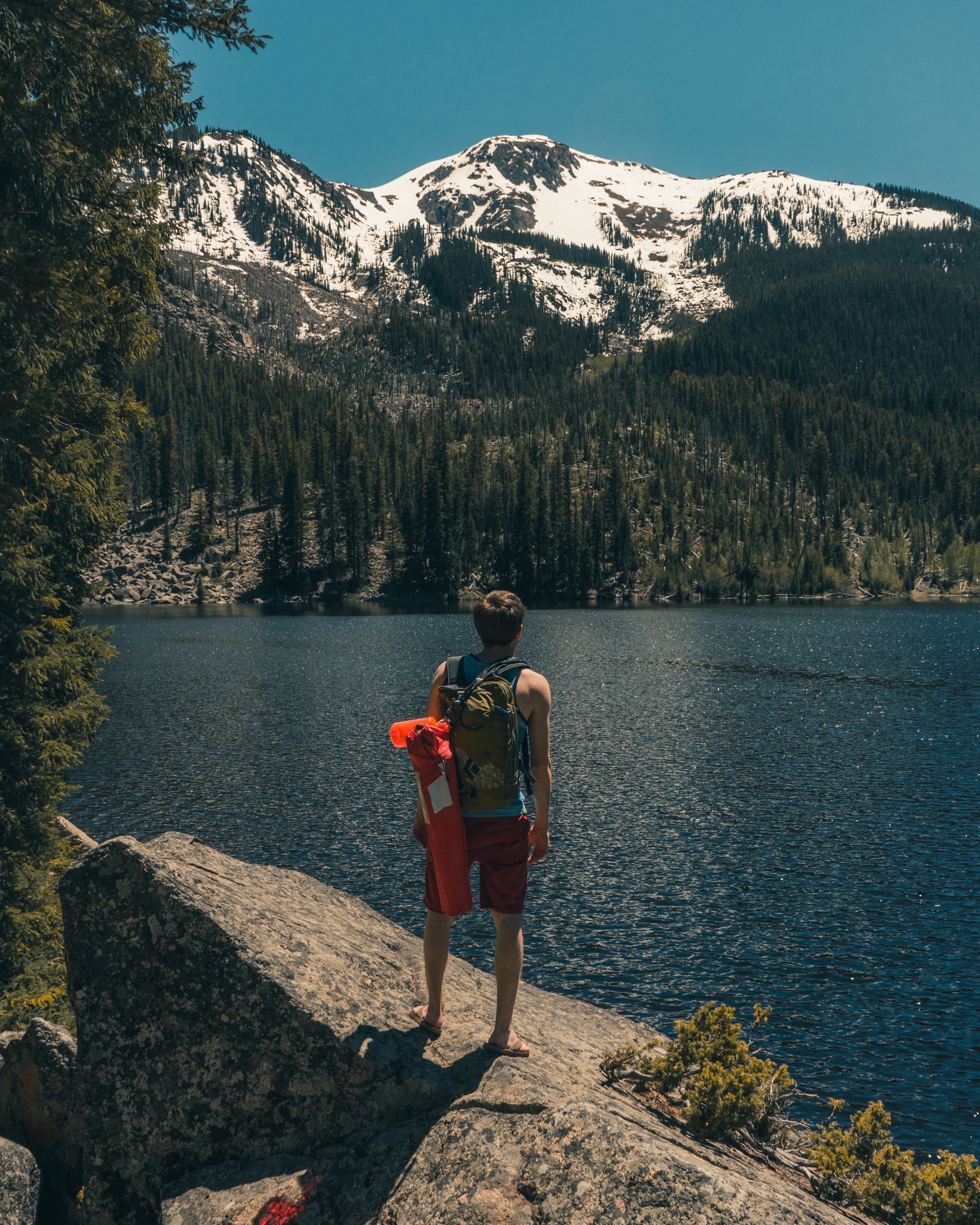 Man with backpack and sleeping bag by a mountain lake HD Wallpaper