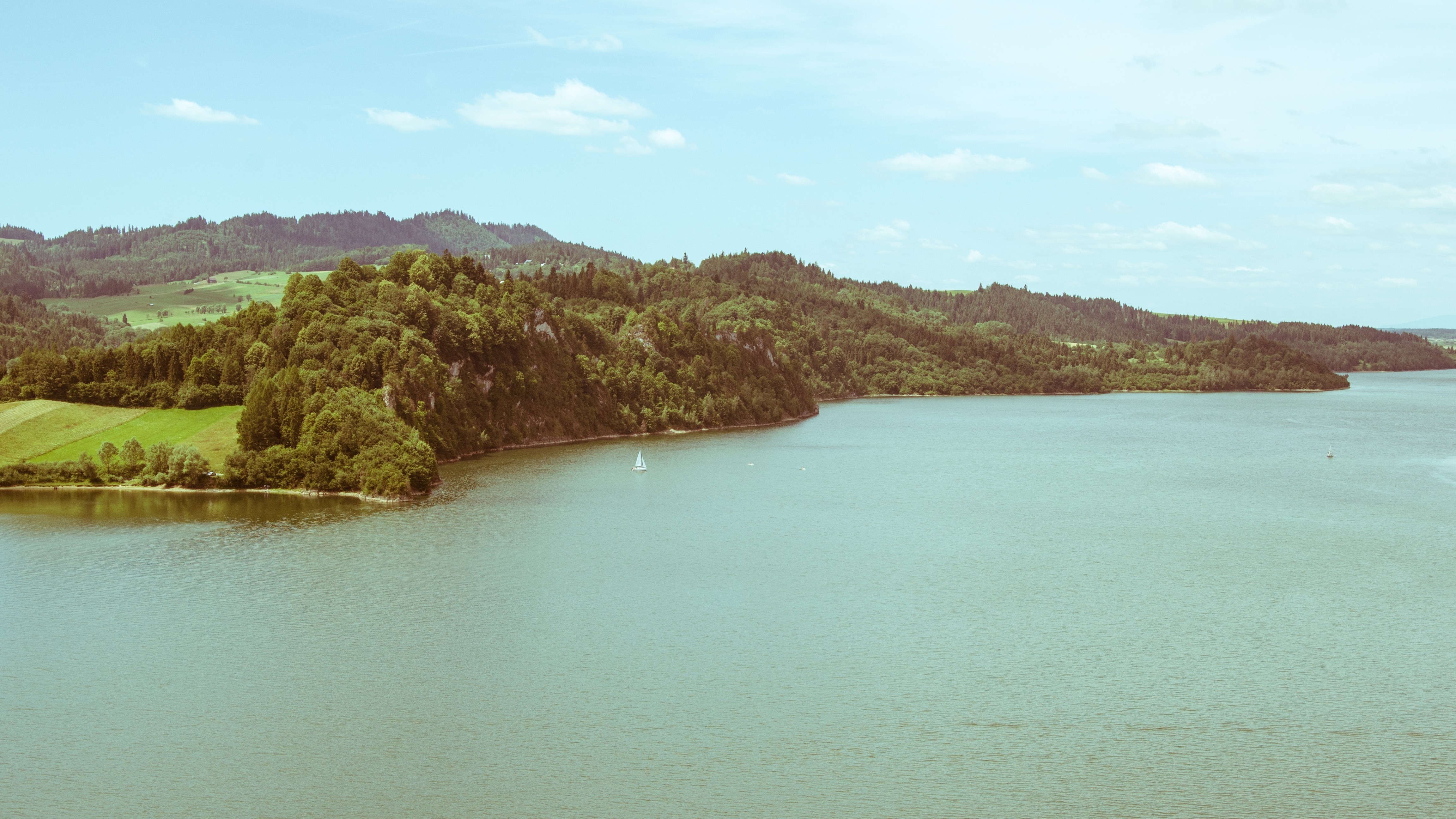 Sailboat on a large lake surrounded by forested hills HD Wallpaper