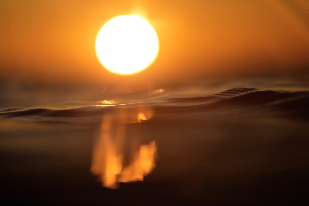 Sun setting over the ocean with reflection HD Wallpaper