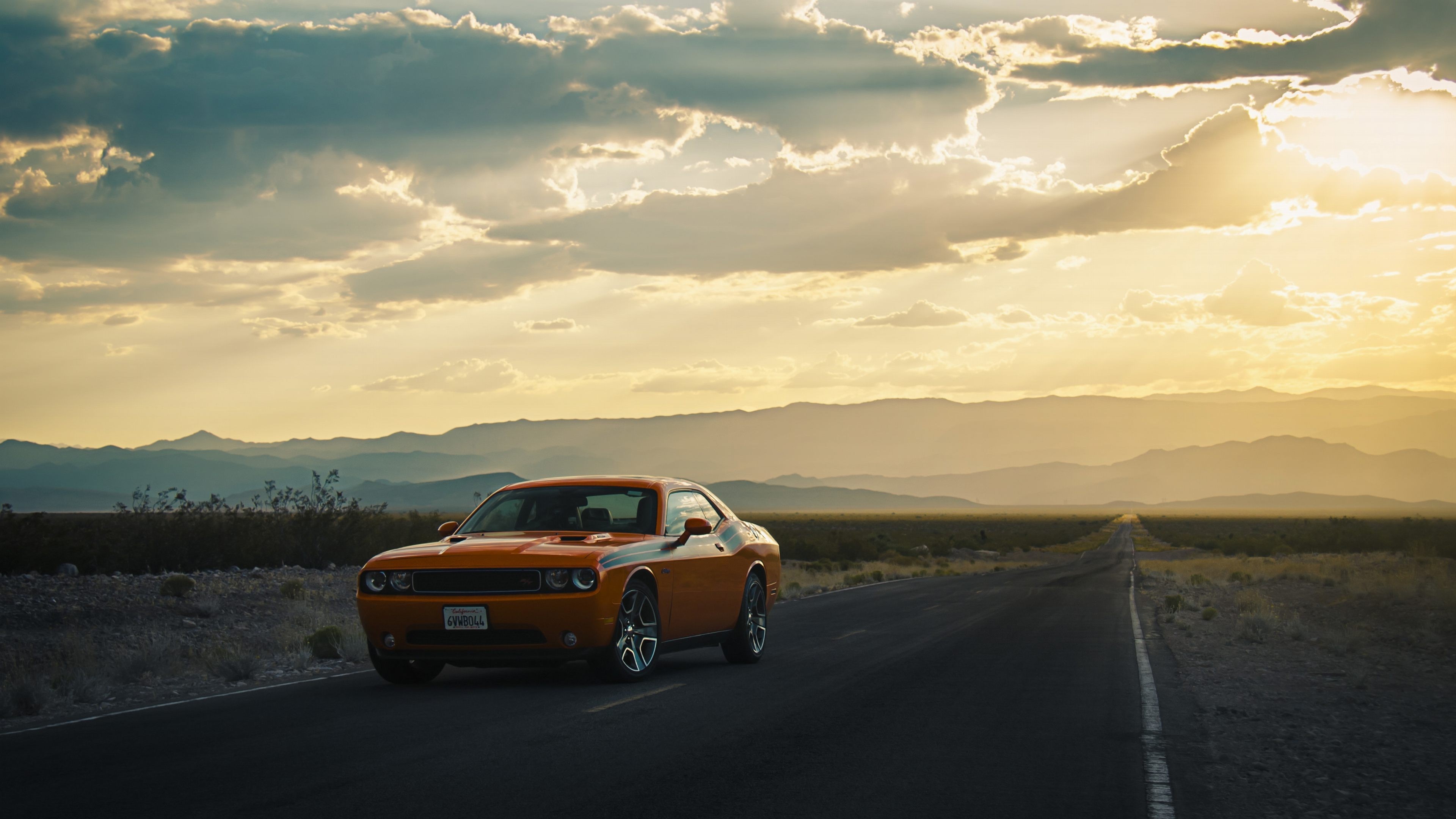Orange Dodge Challenger on a desert road at sunset HD Wallpaper