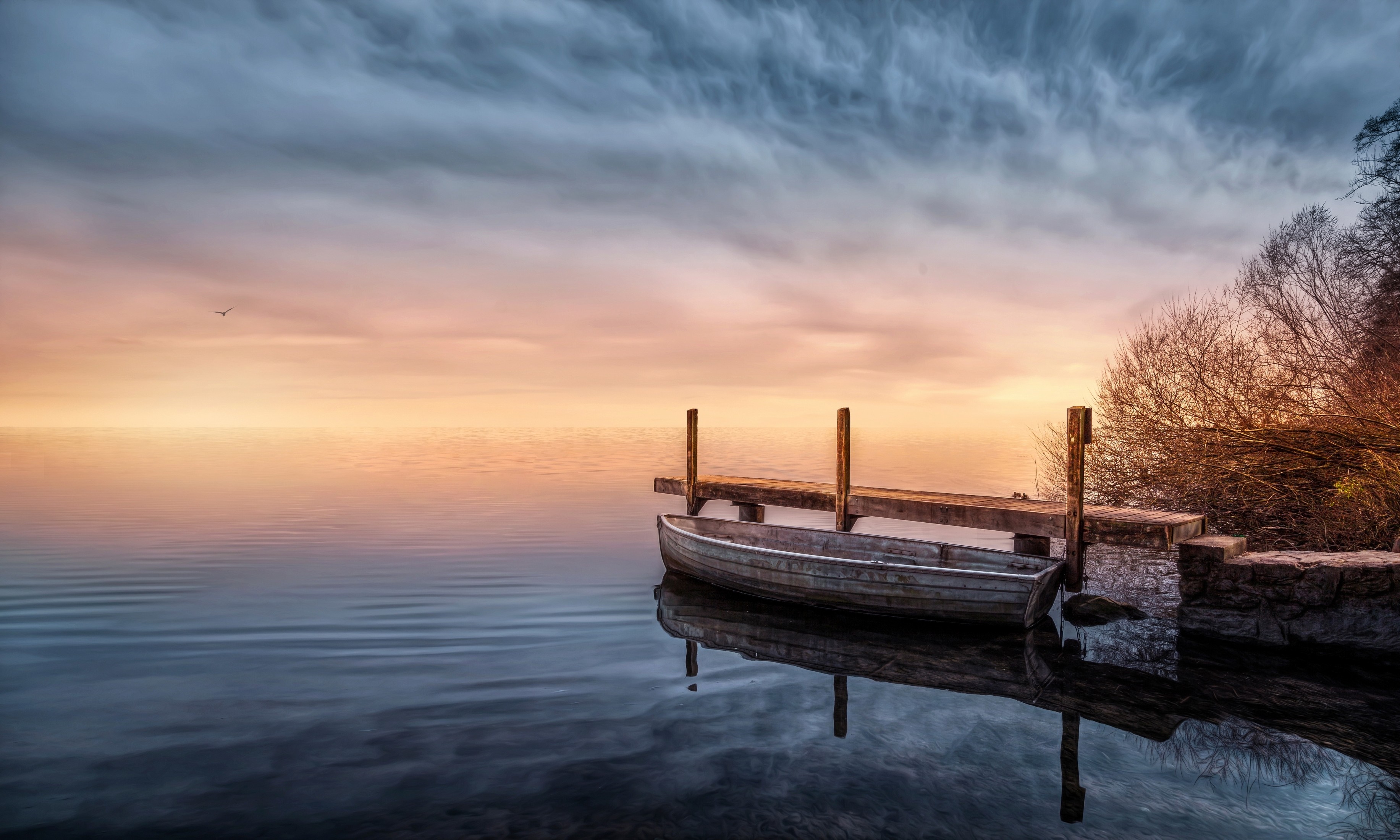 Boat docked at a pier during sunset over a calm lake HD Wallpaper