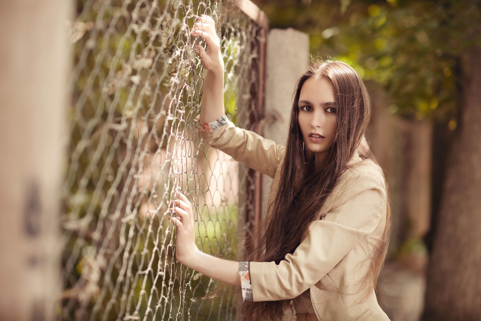 Woman leaning on a chain-link fence HD Wallpaper