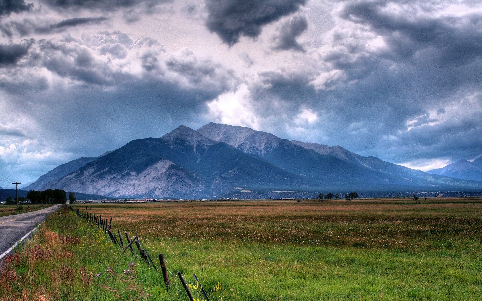 Stormy clouds over mountains and a field HD Wallpaper