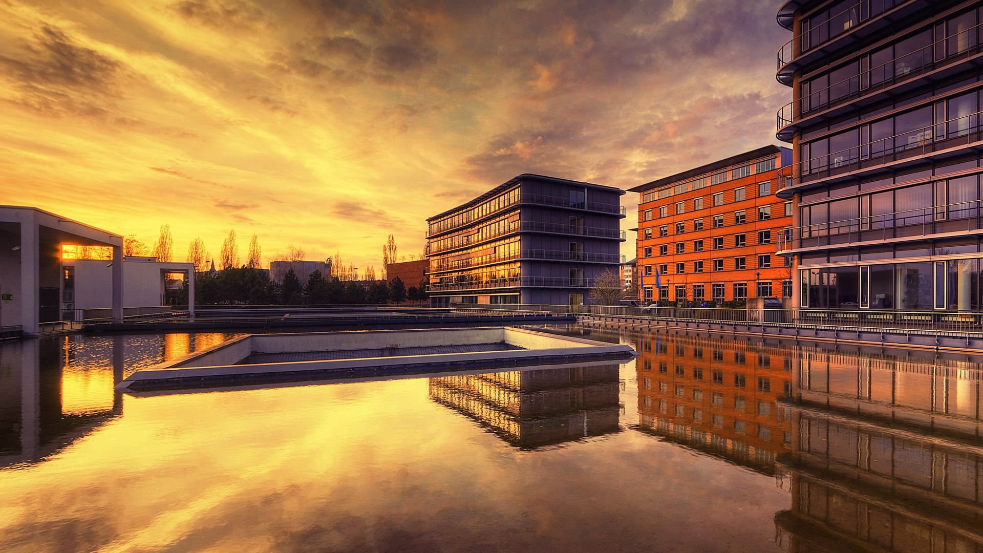 Modern buildings reflected in water at sunset HD Wallpaper