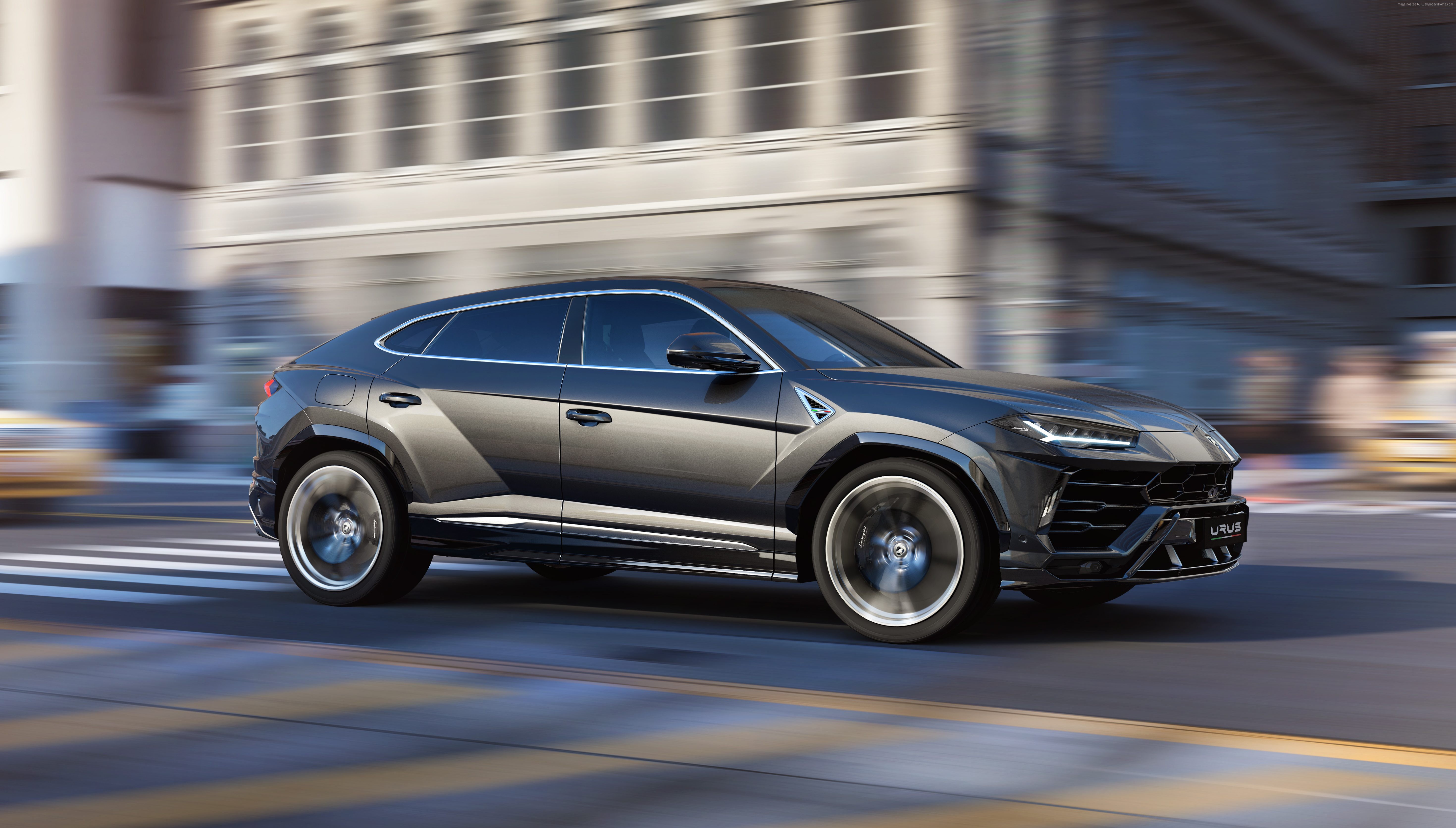 Lamborghini Urus driving on city street HD Wallpaper