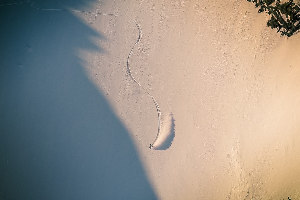 Snowboarder carving a turn in a snowy landscape HD Wallpaper