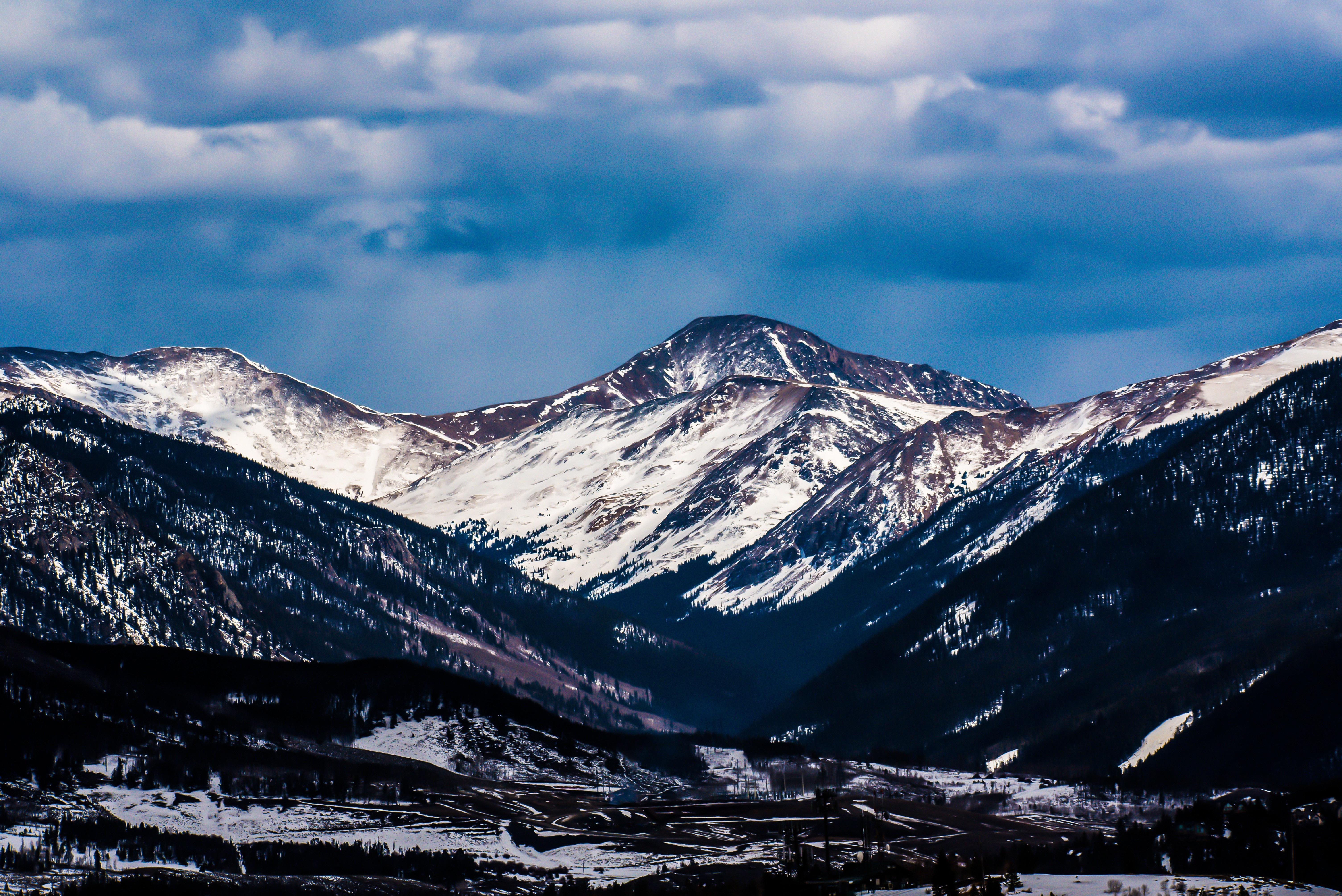 Snow-covered mountains under a cloudy sky HD Wallpaper