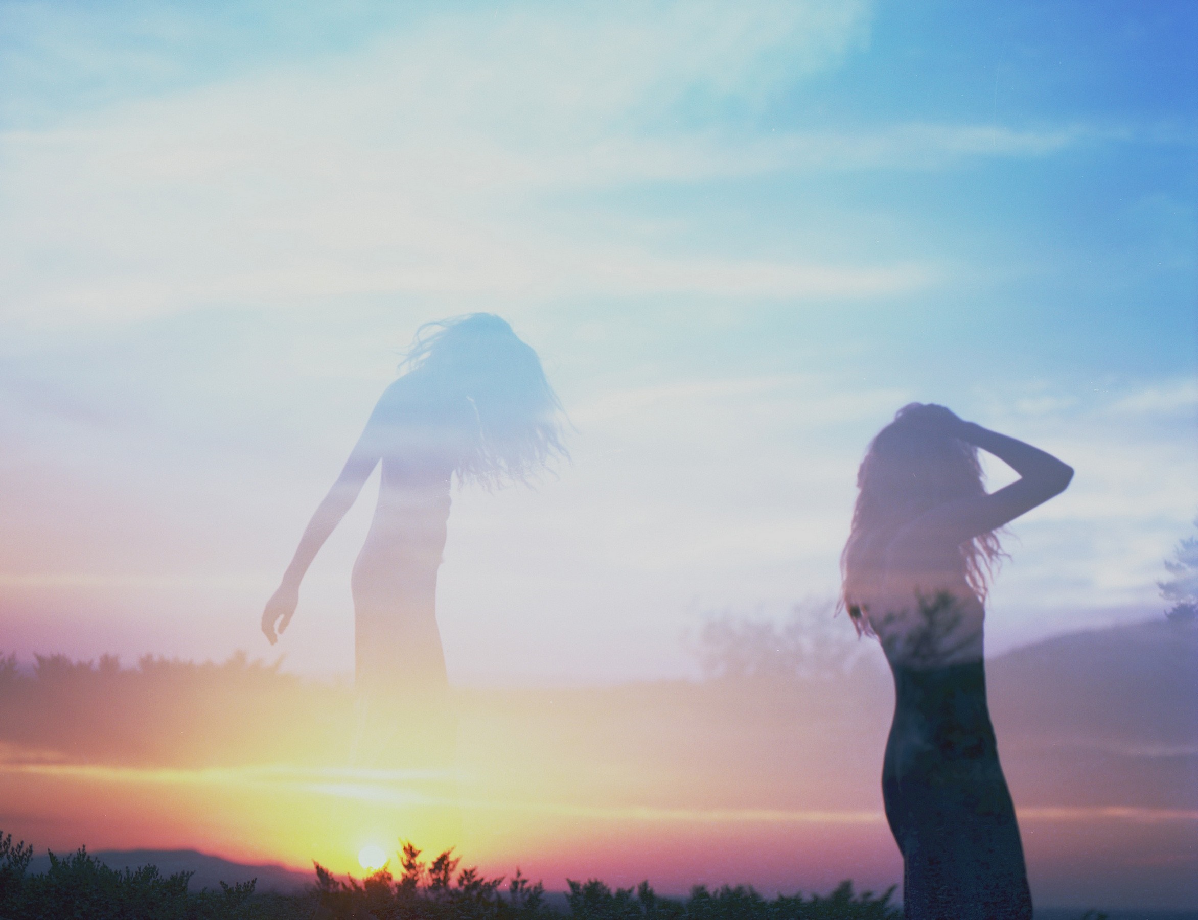 Two women silhouetted against a sunset sky HD Wallpaper