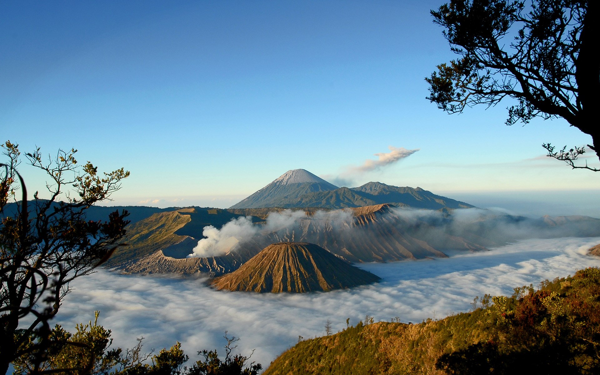 Volcanoes shrouded in mist under a clear blue sky HD Wallpaper