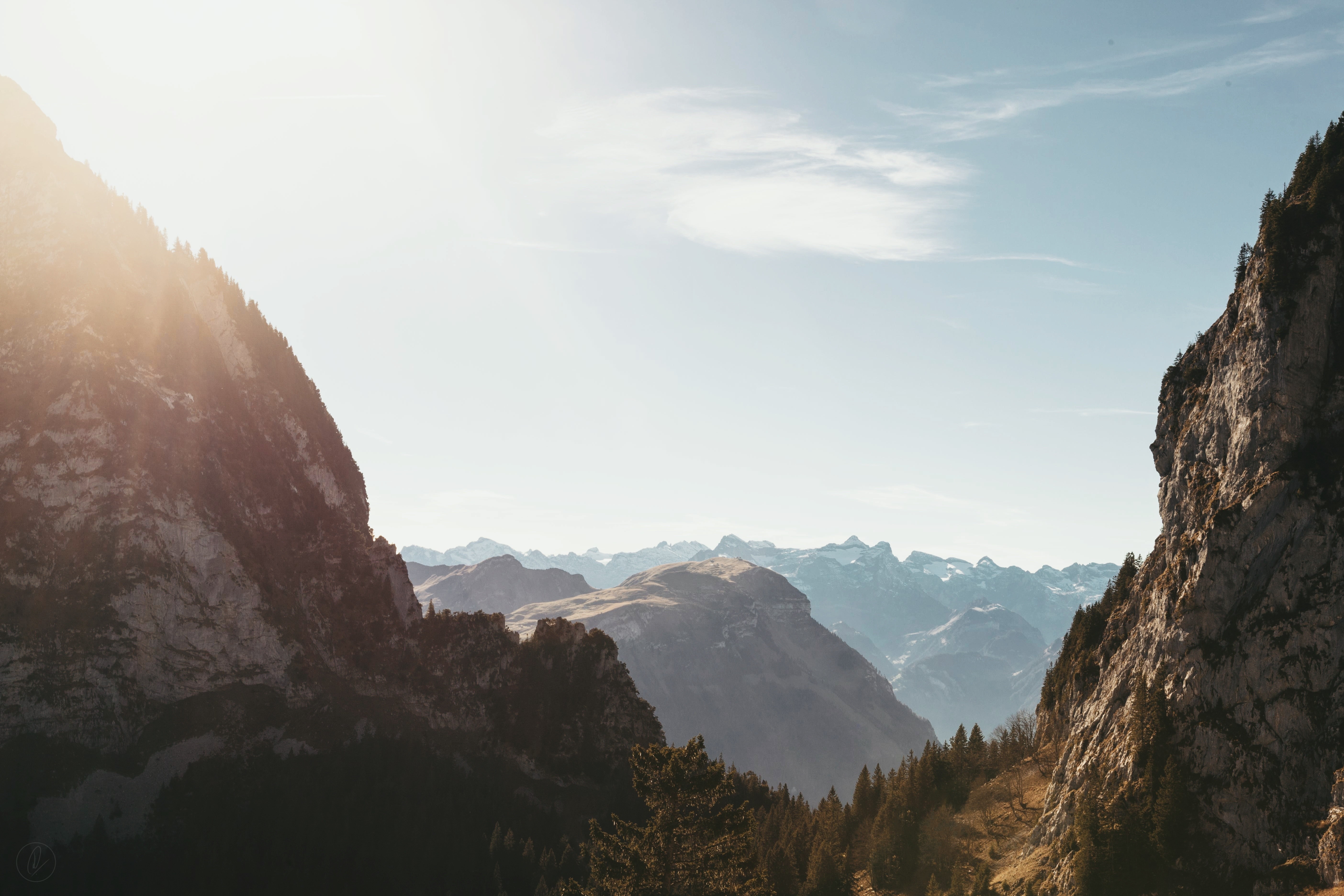Sunlight over a mountain valley with rocky cliffs HD Wallpaper