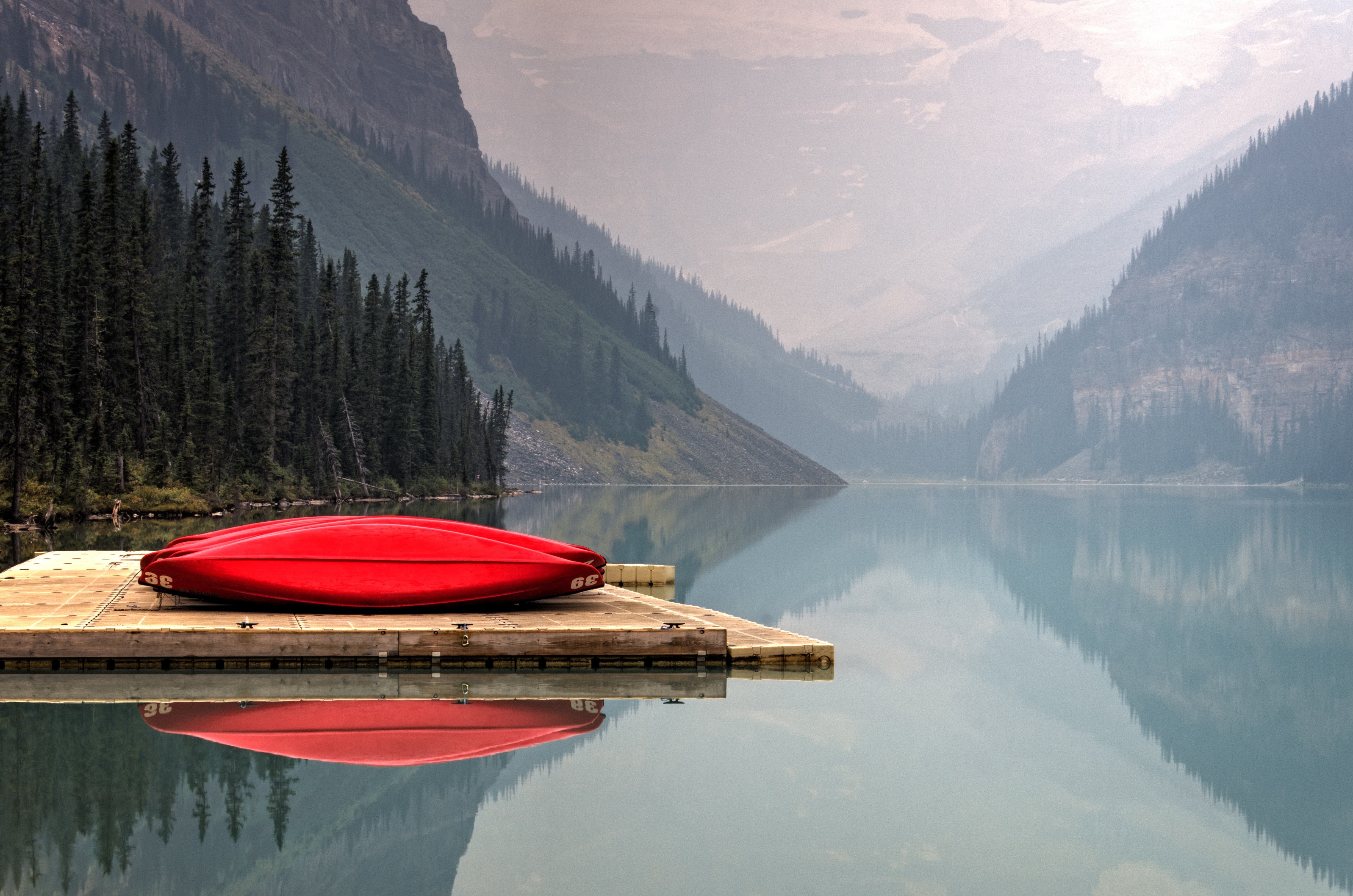 Red canoe on a dock at a misty mountain lake HD Wallpaper