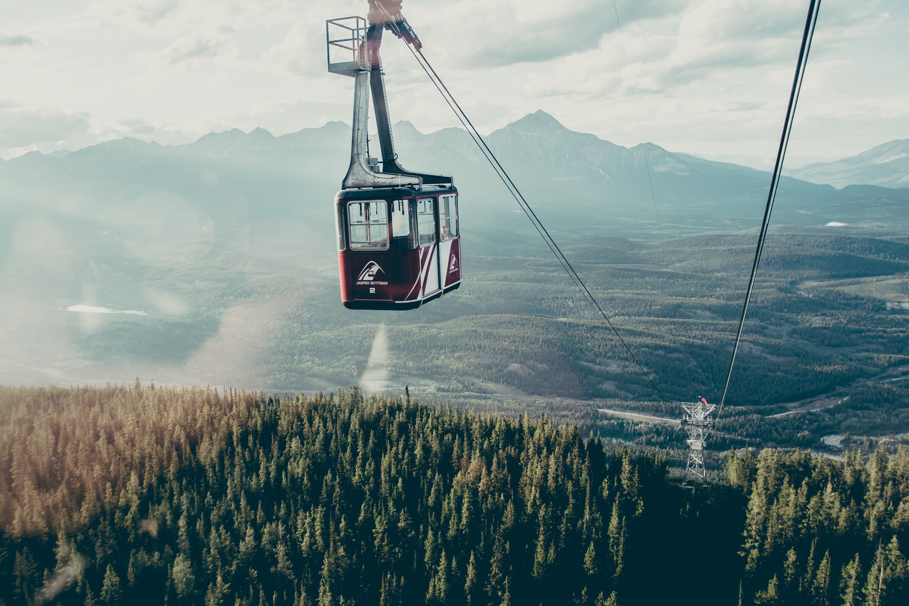 Cable car over a forest with mountains in the background HD Wallpaper