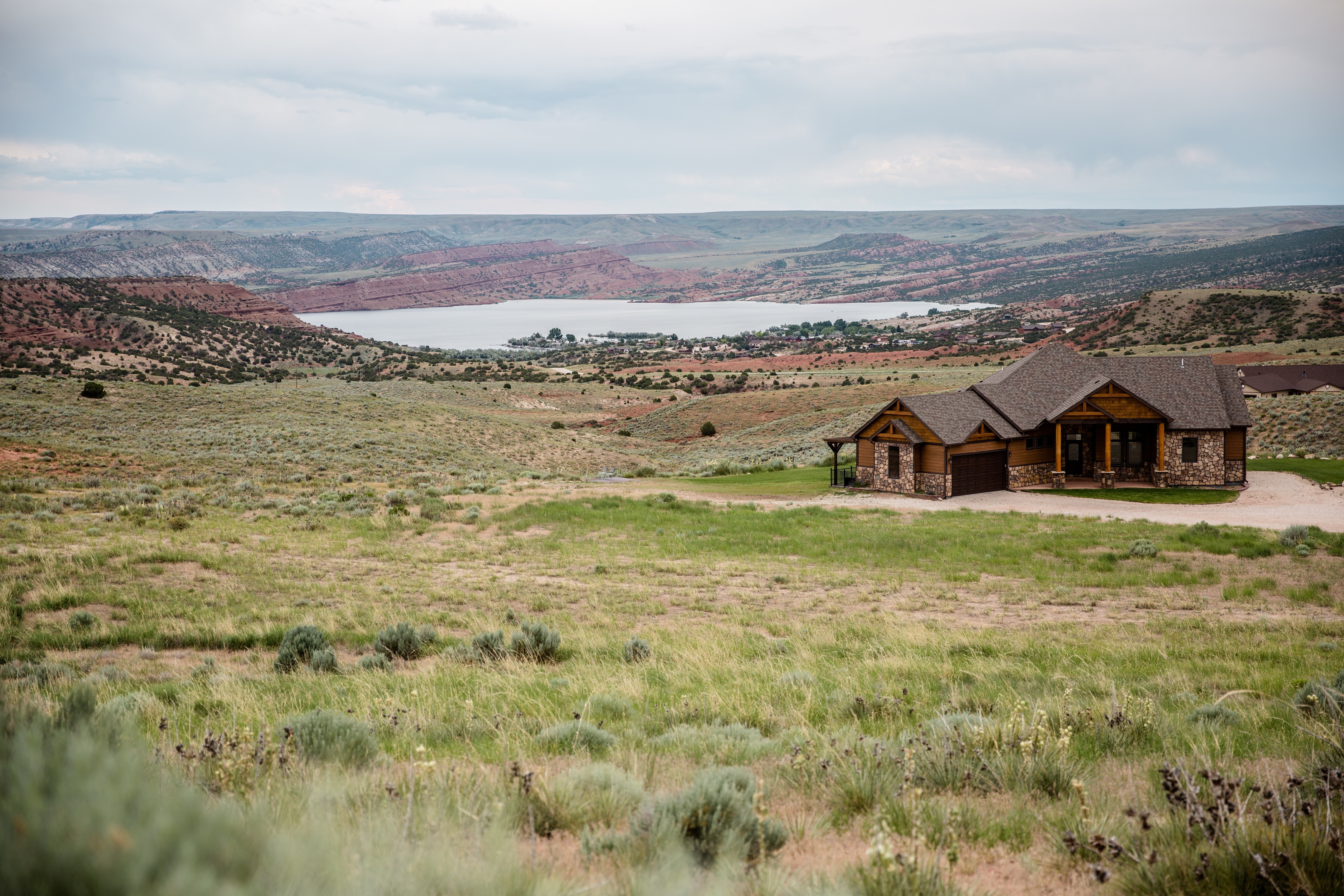 House overlooking a lake and red rock formations HD Wallpaper