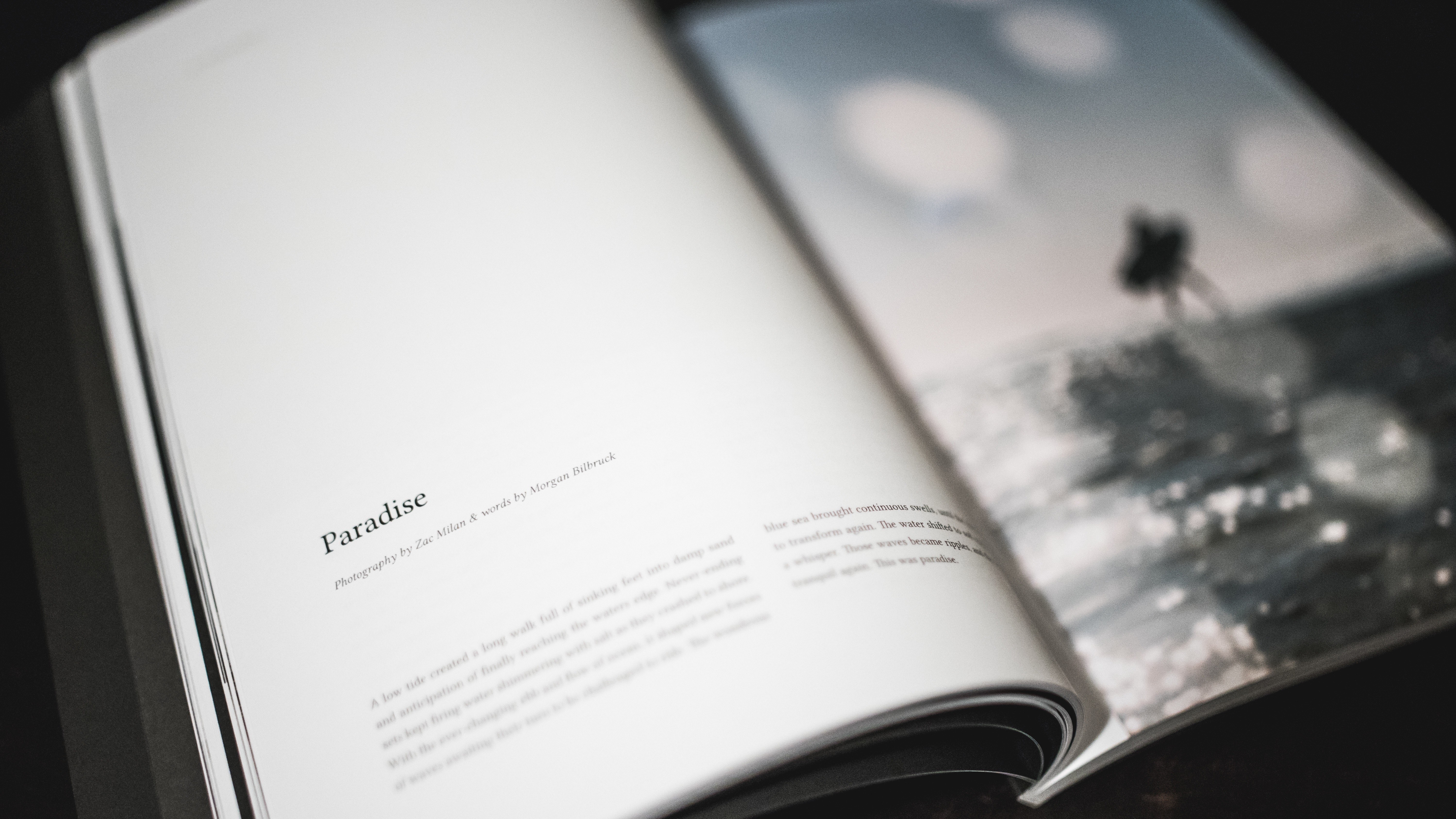 Book with "Paradise" title and ocean photograph HD Wallpaper