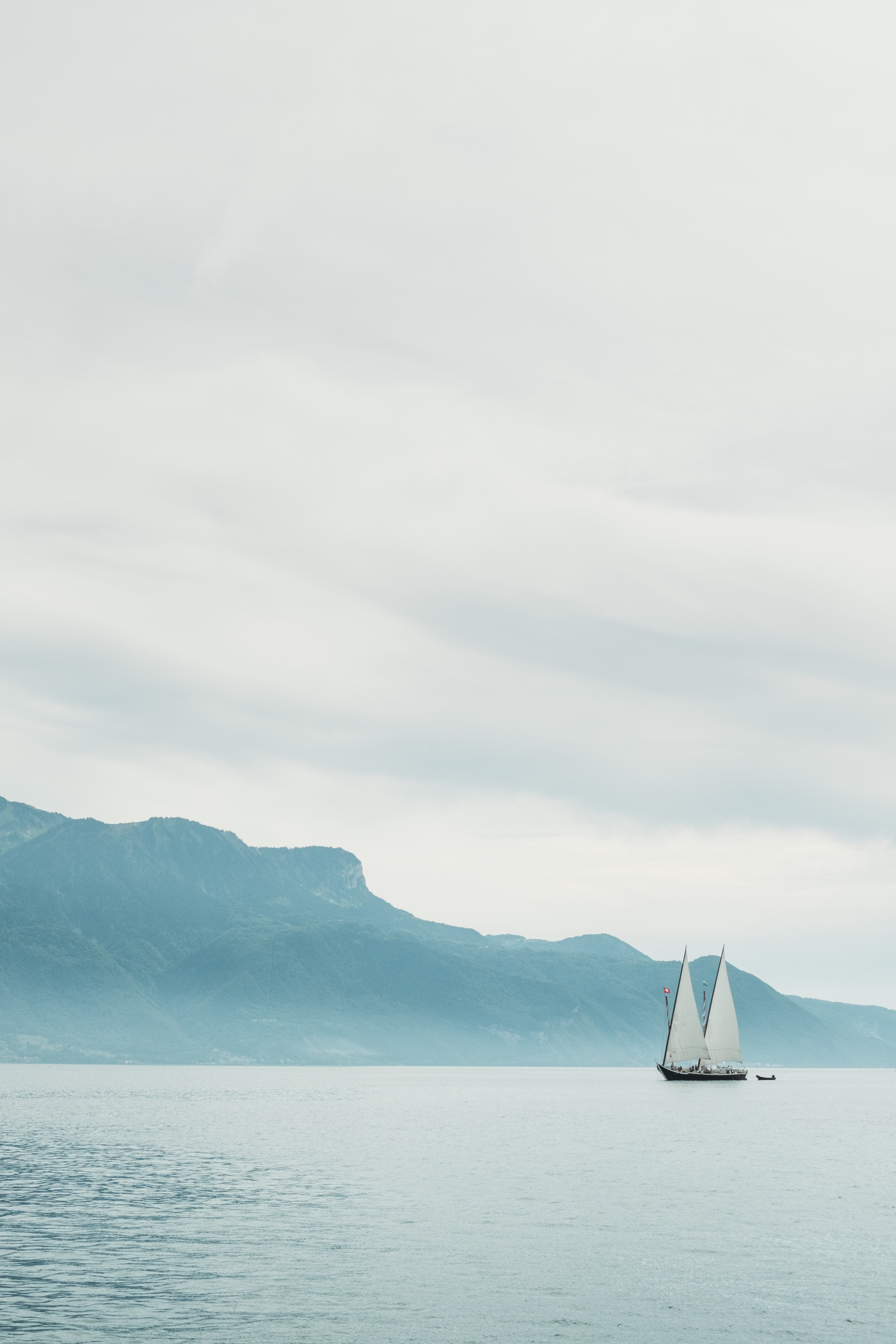 Sailboat on a calm lake with mountains in the background HD Wallpaper