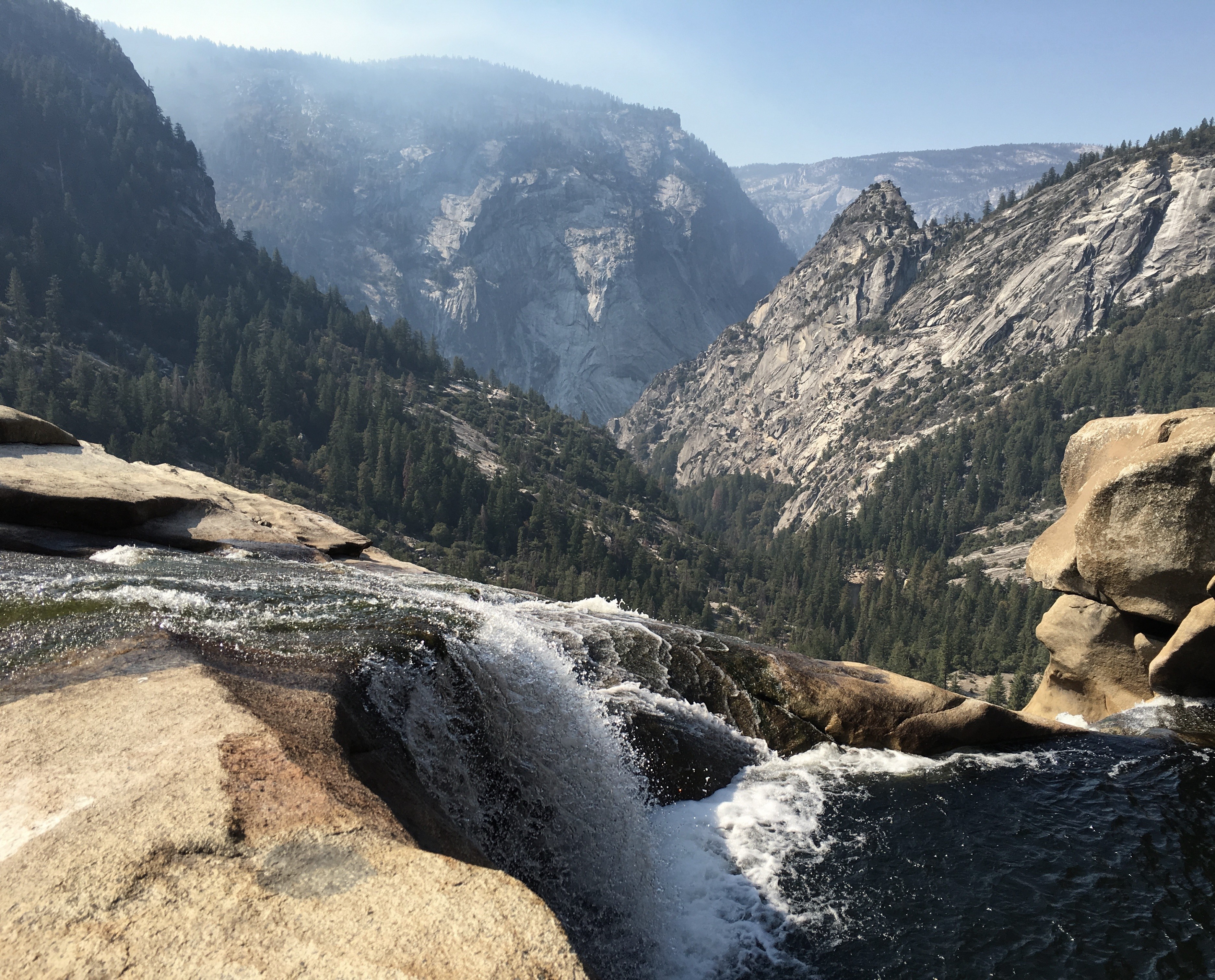 Waterfall overlooking a forested mountain valley HD Wallpaper
