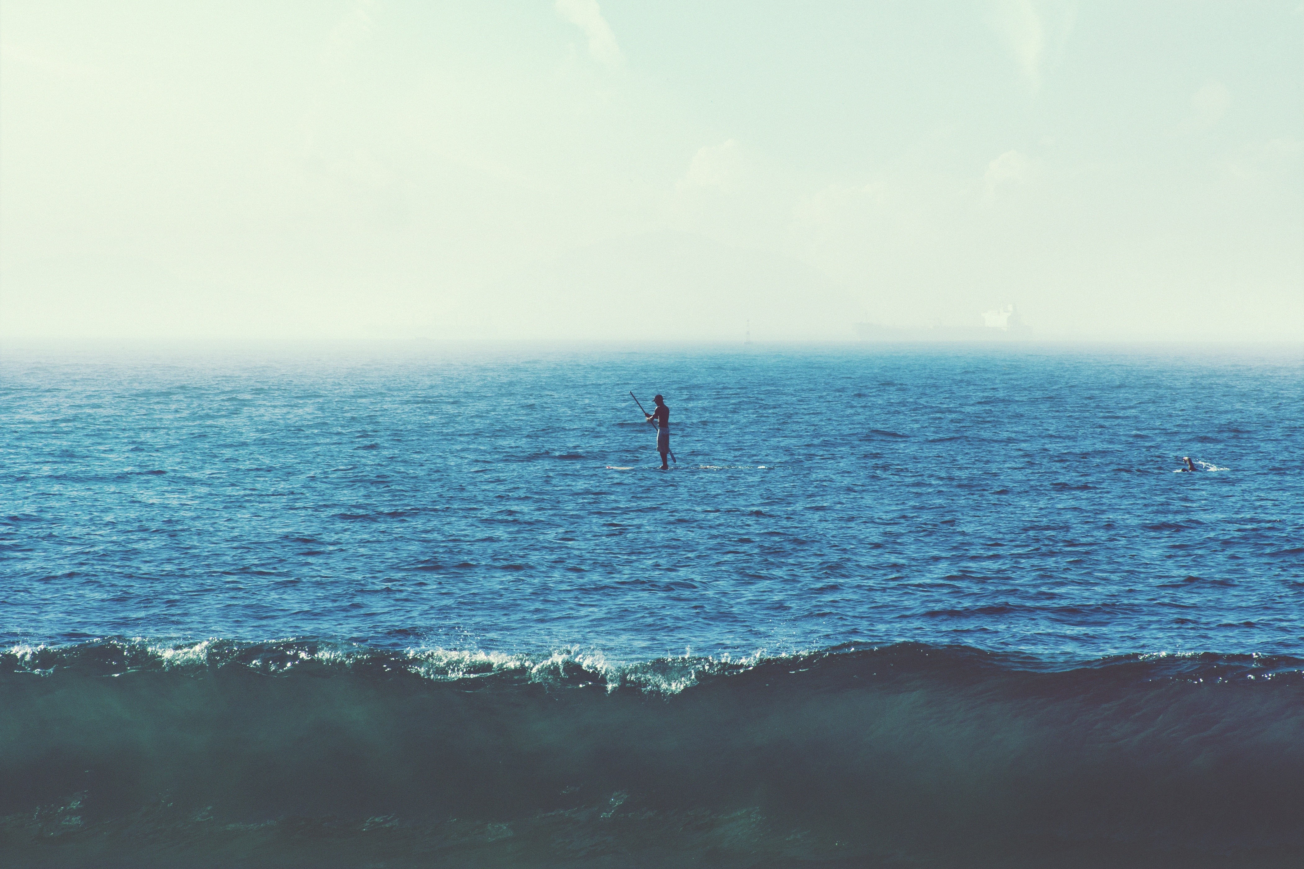 Person paddleboarding on the ocean with waves HD Wallpaper