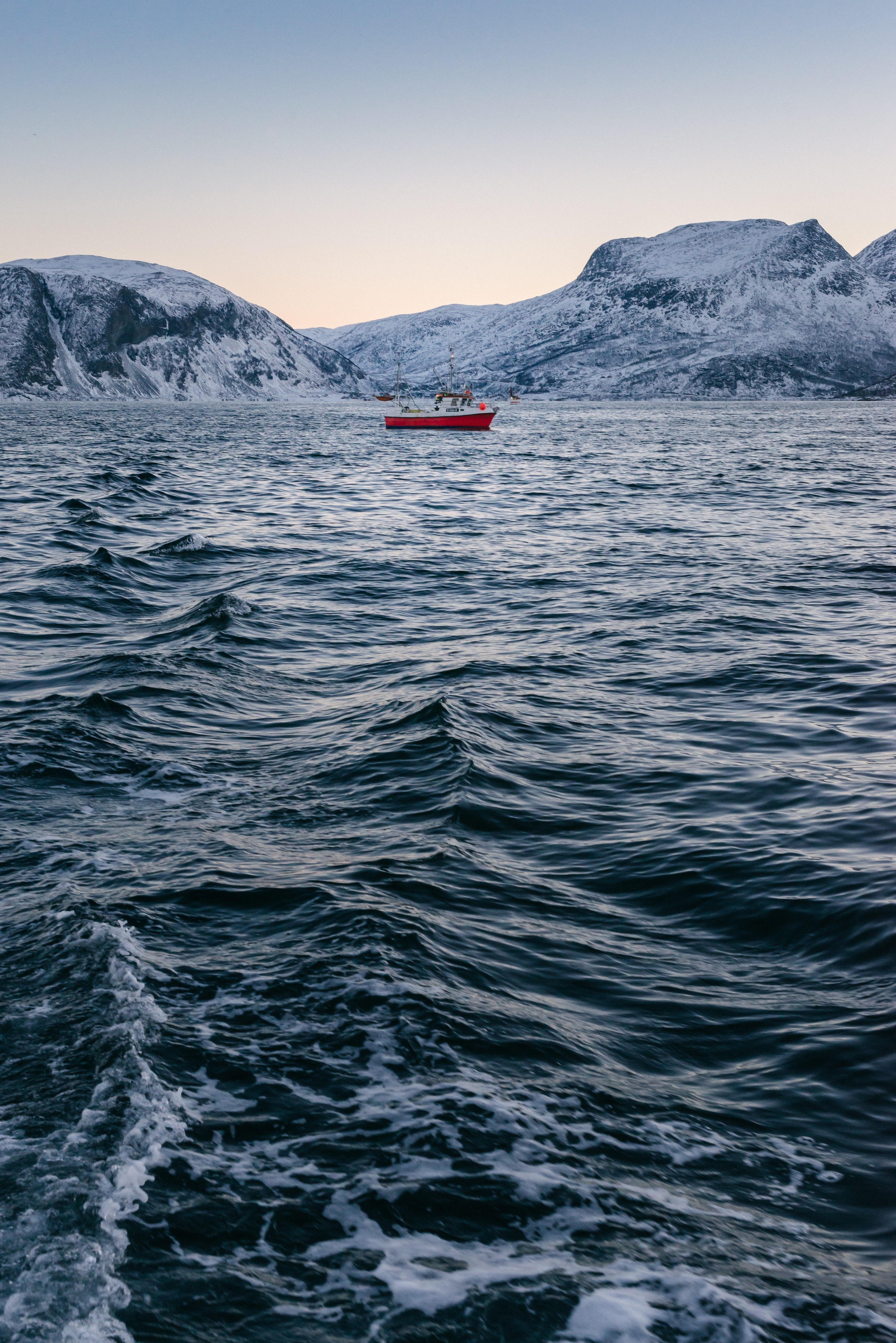 Red boat on a cold sea with snow-capped mountains HD Wallpaper