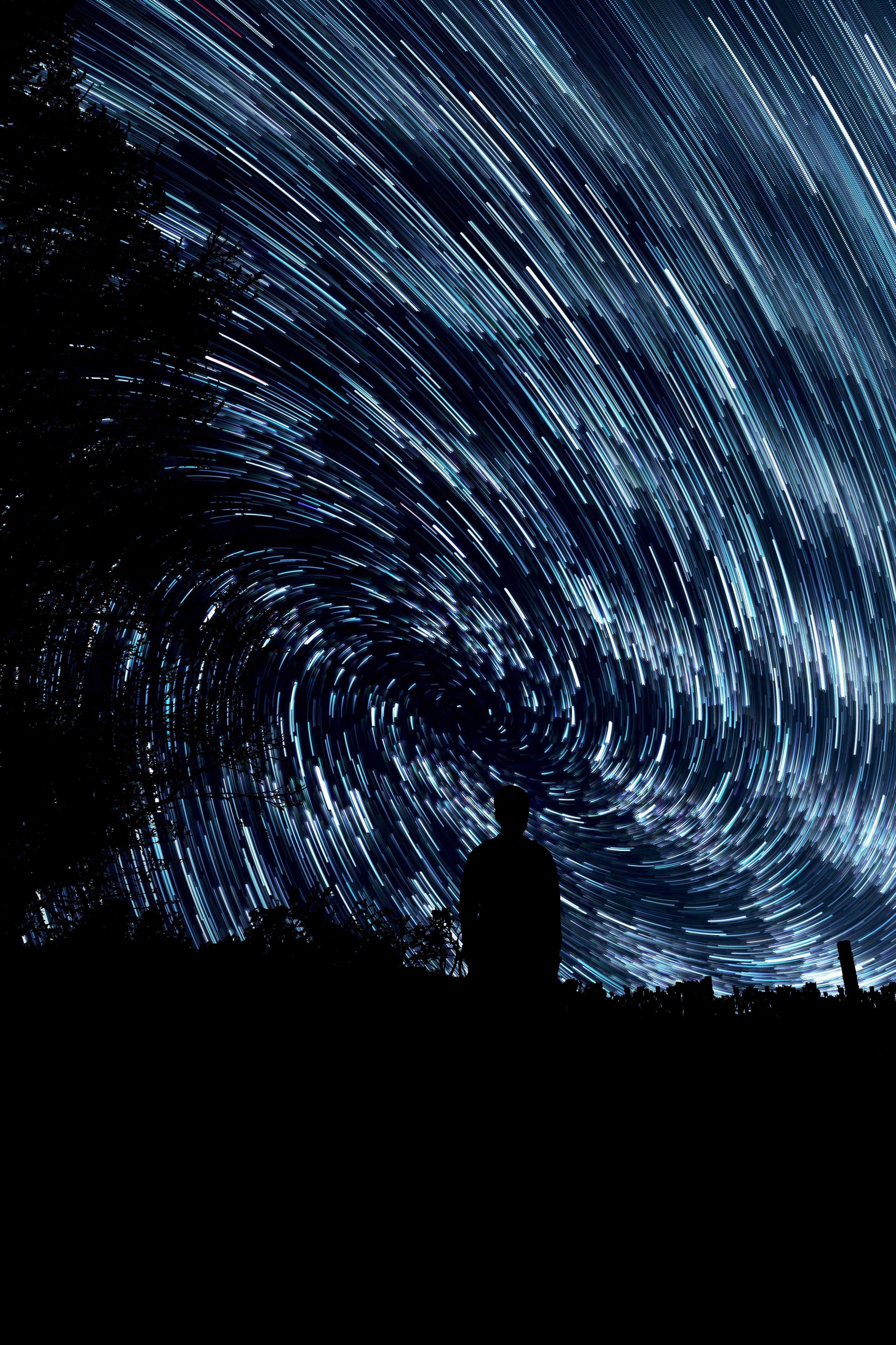 Silhouette of a person under star trails vortex HD Wallpaper