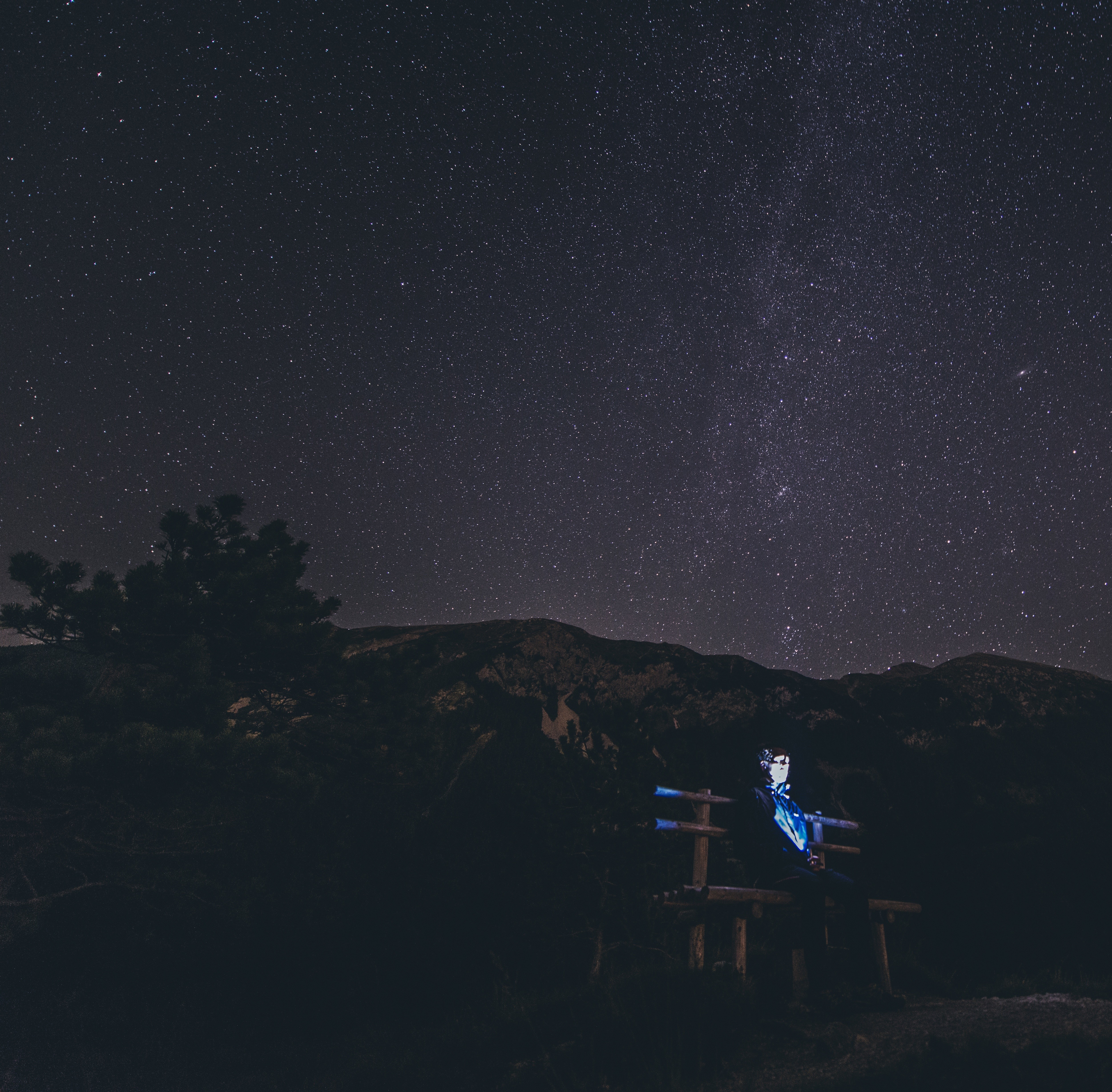 Man sitting on a bench under the stars HD Wallpaper
