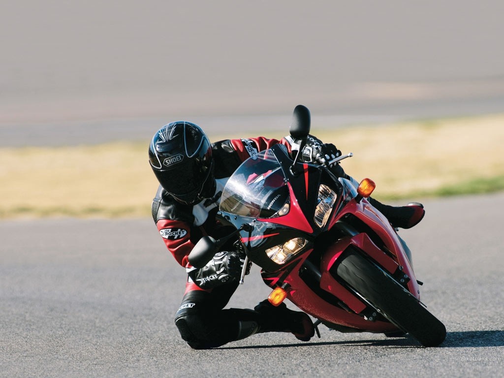 Motorcyclist in full gear leaning into a turn on a red Honda motorcycle HD Wallpaper