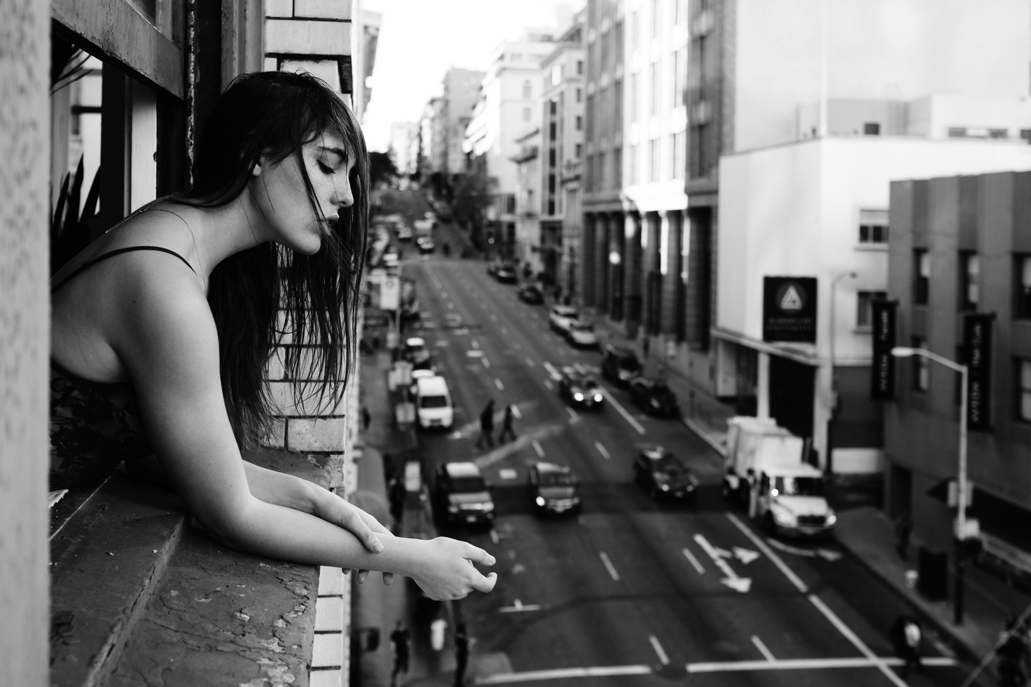 Woman looking out a window at a city street HD Wallpaper