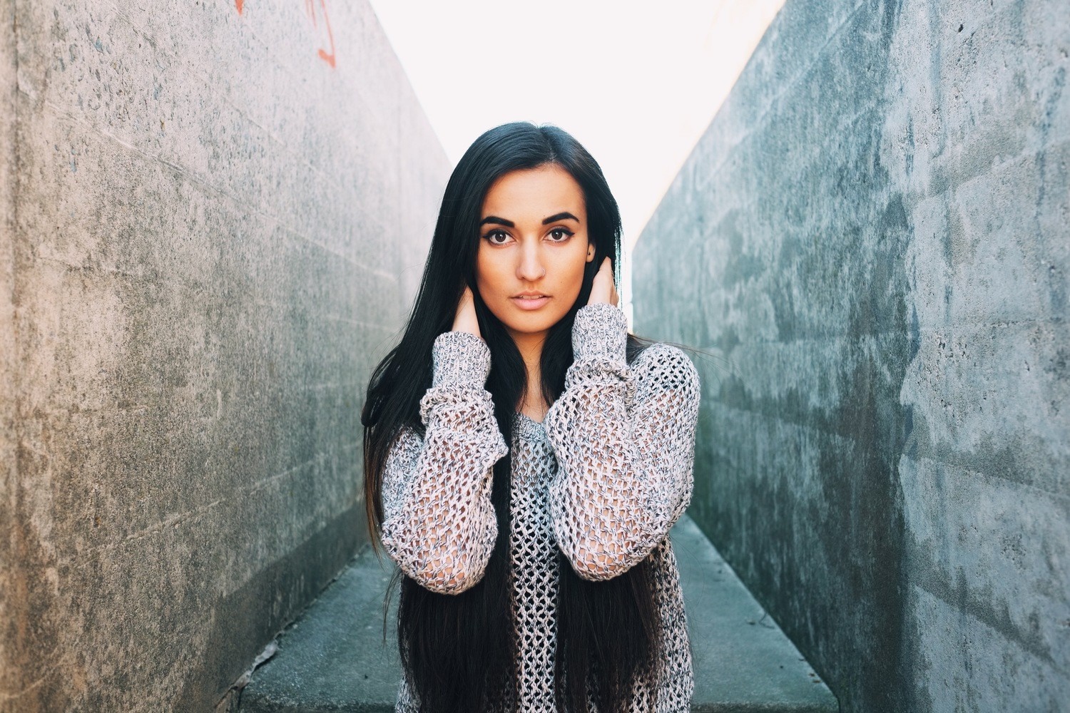 Woman in a knitted sweater standing between concrete walls HD Wallpaper