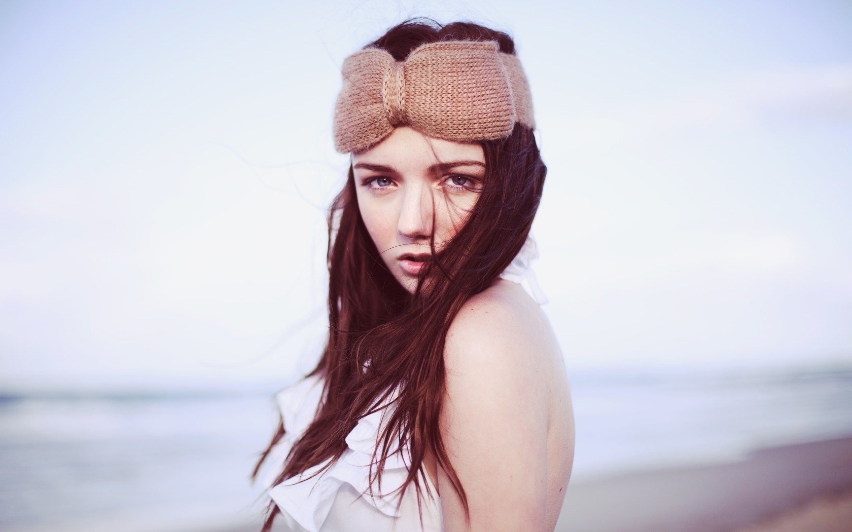 Woman with brown hair wearing a knitted headband on the beach HD Wallpaper