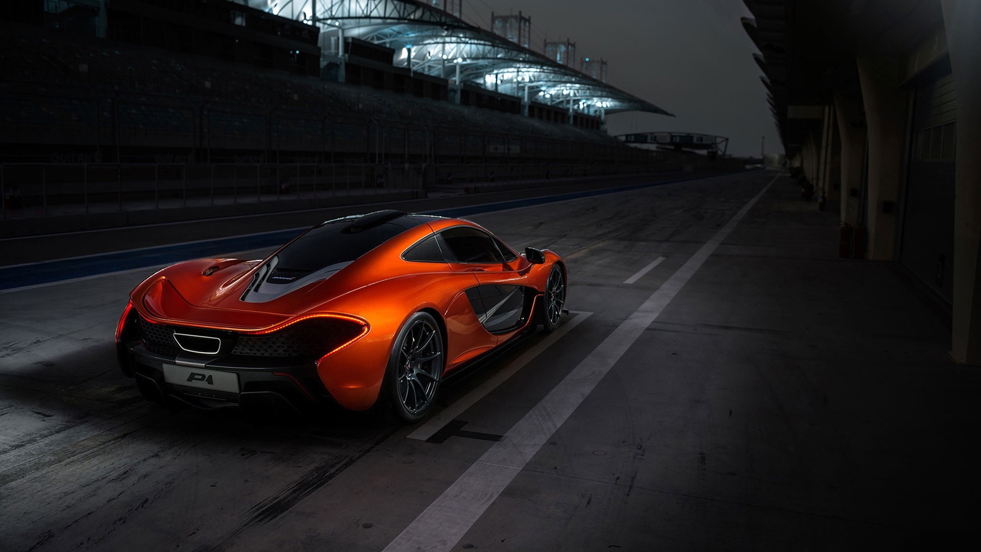Orange McLaren P1 sports car on a racetrack at night HD Wallpaper