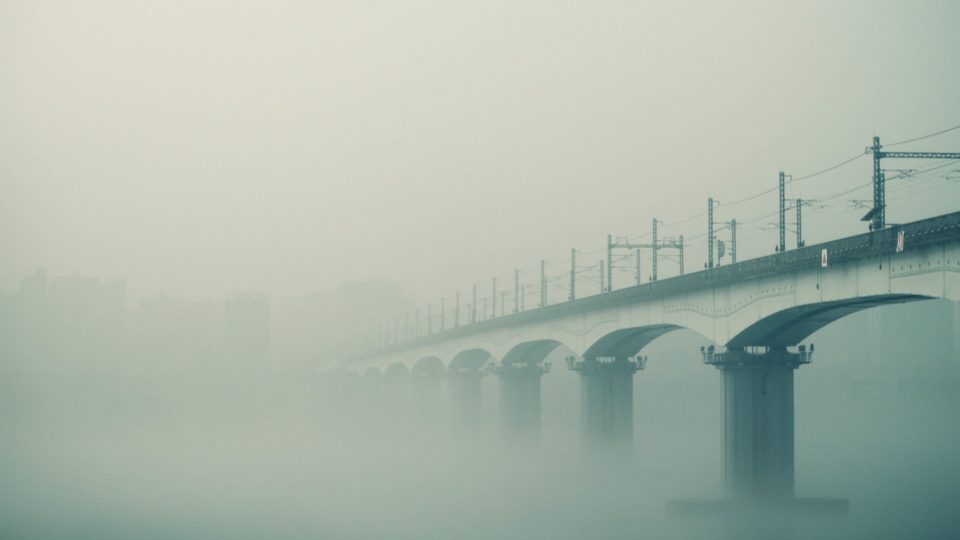 Bridge in fog with city skyline HD Wallpaper