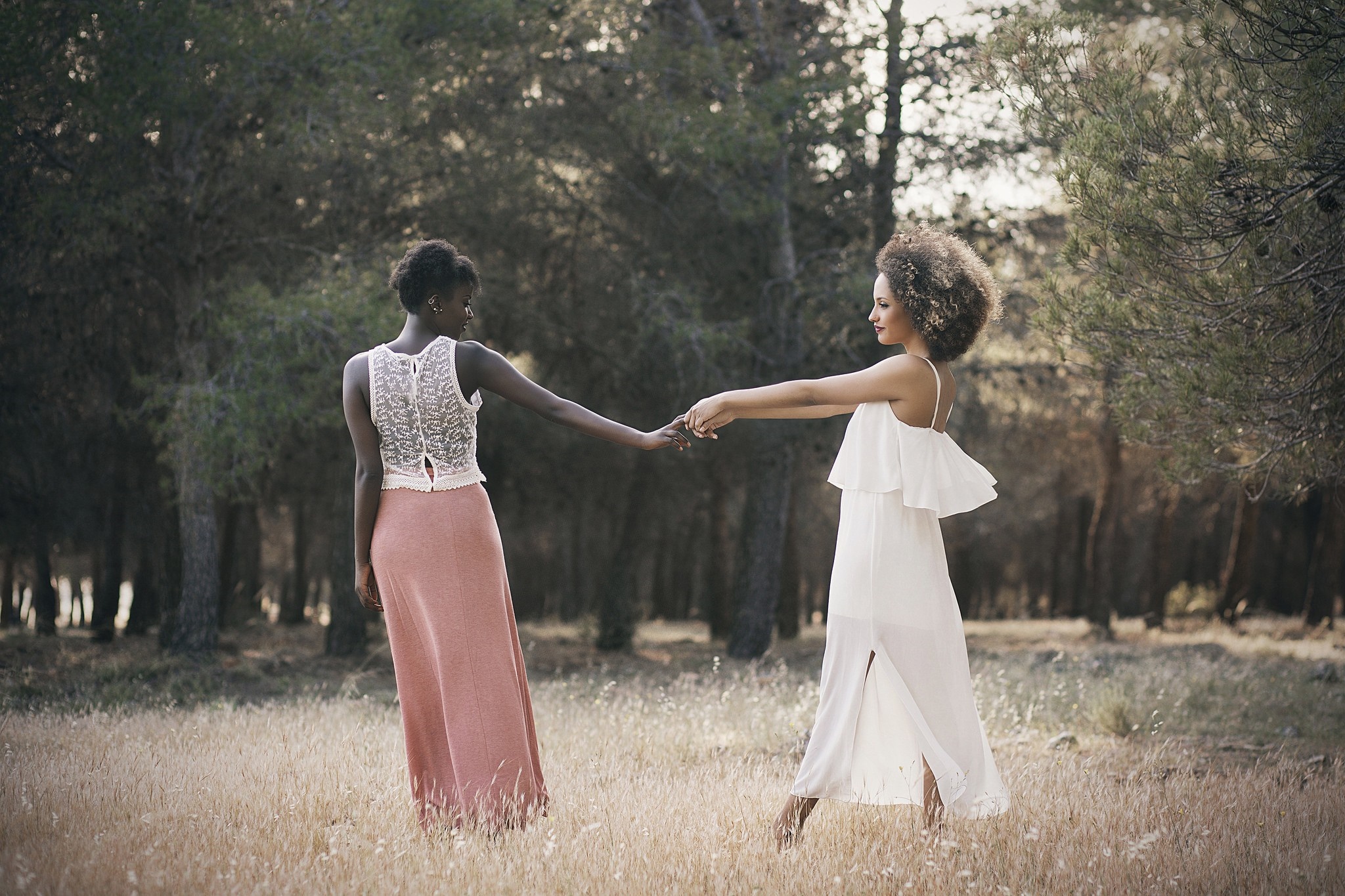 Two women holding hands in a forest HD Wallpaper