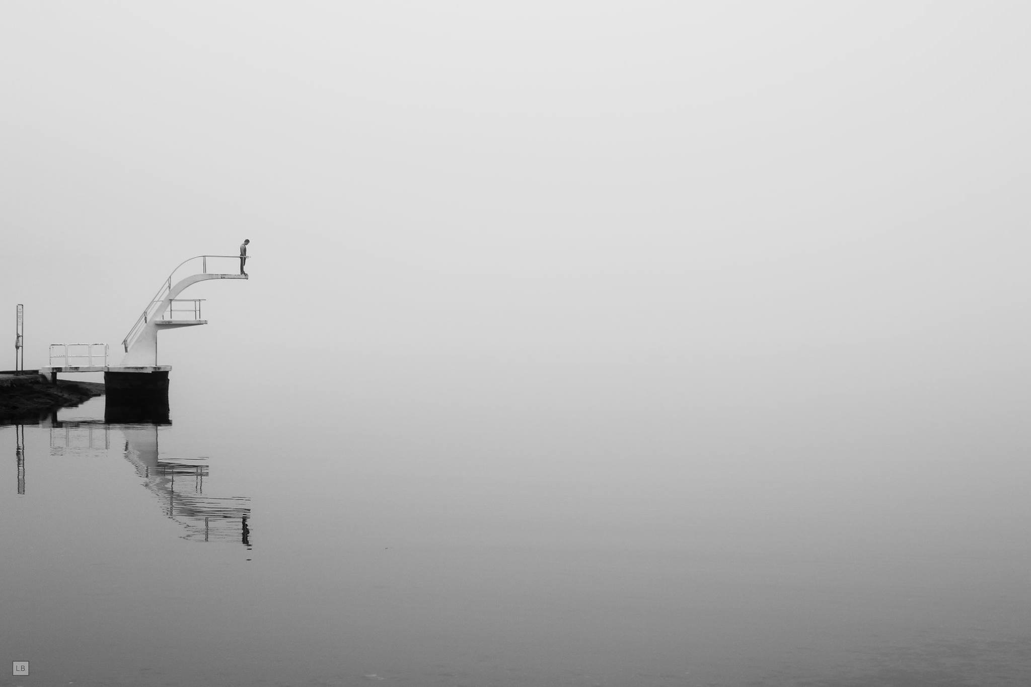 Person on diving board in fog over water HD Wallpaper