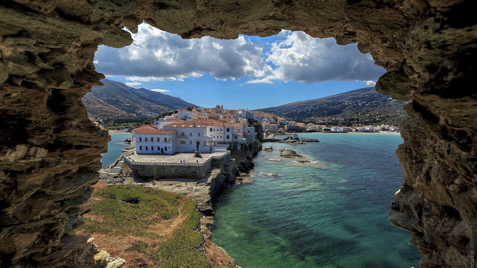 View of a coastal town through a rock arch HD Wallpaper