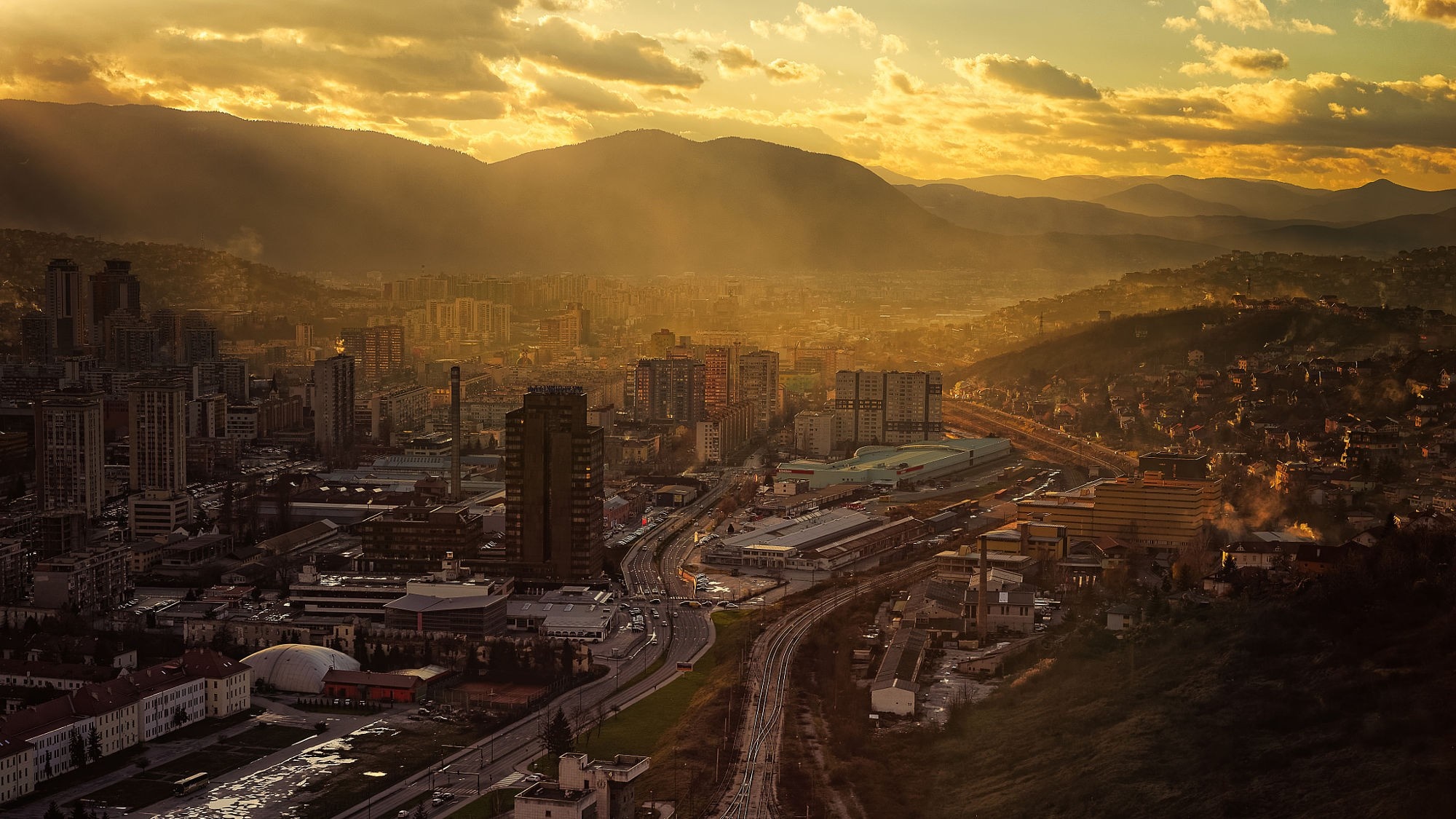 Aerial view of Sarajevo at sunset with mountains in the background HD Wallpaper