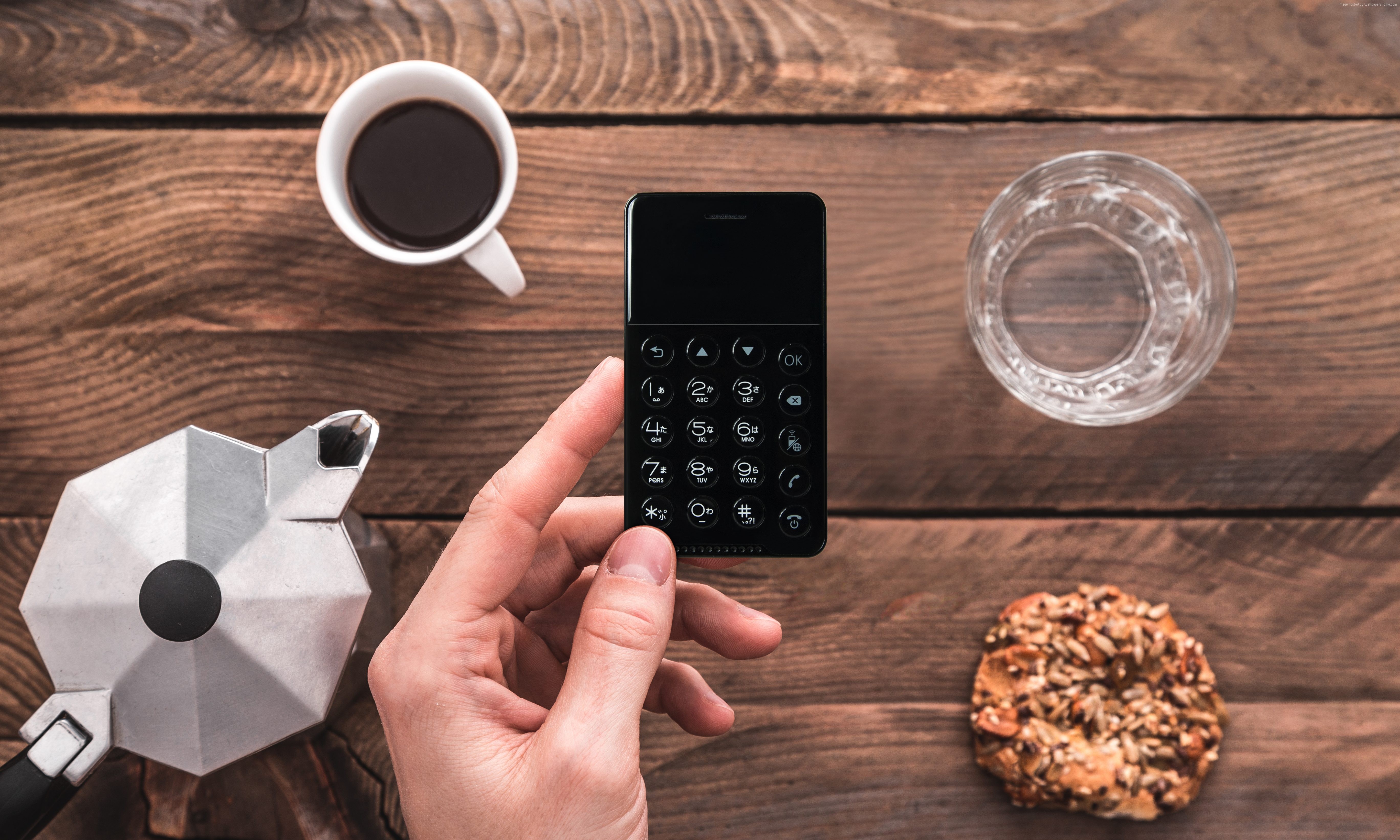 NichePhone-S held by hand with coffee and pastry HD Wallpaper