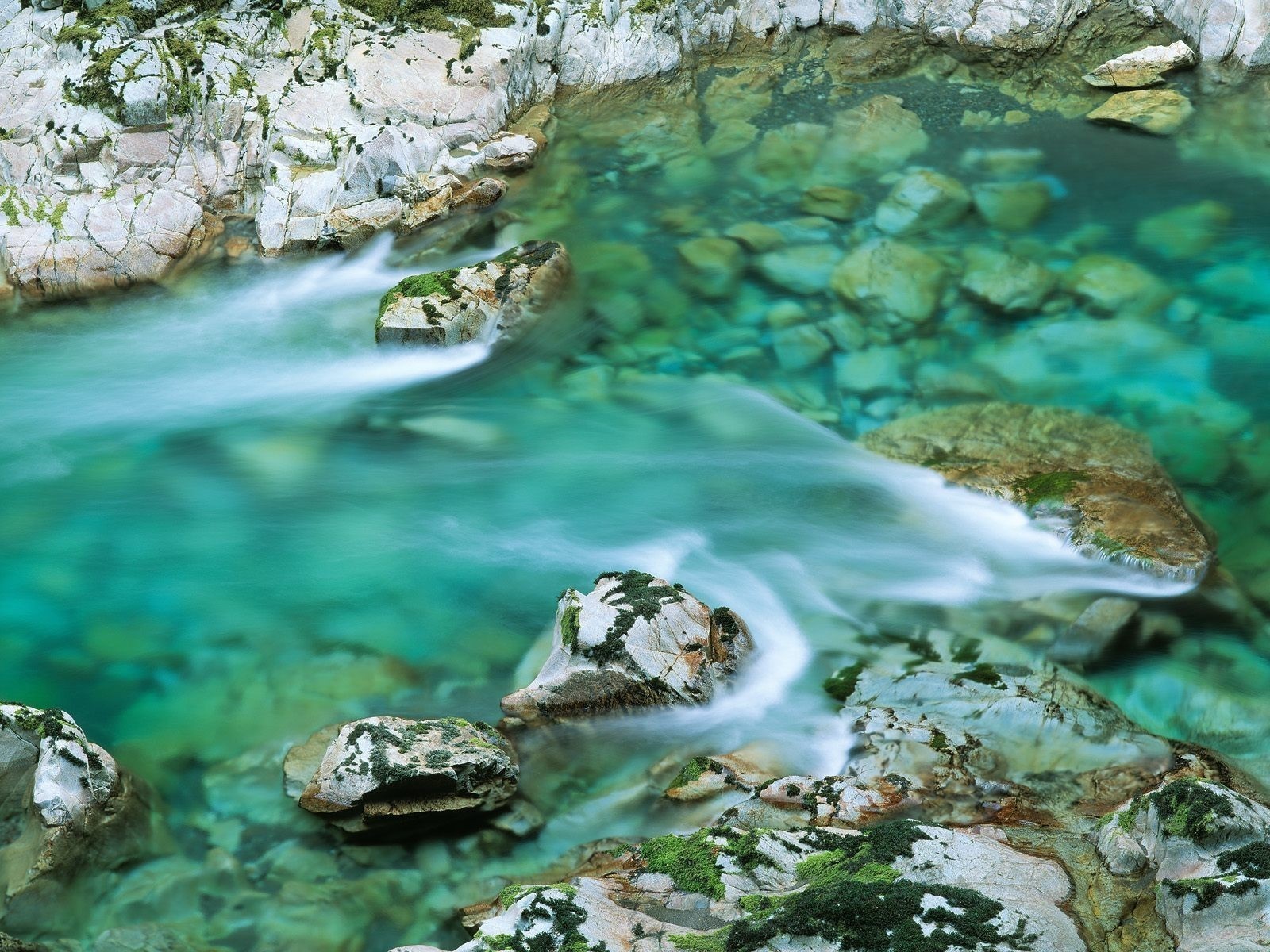 Clear turquoise river flowing over rocks HD Wallpaper