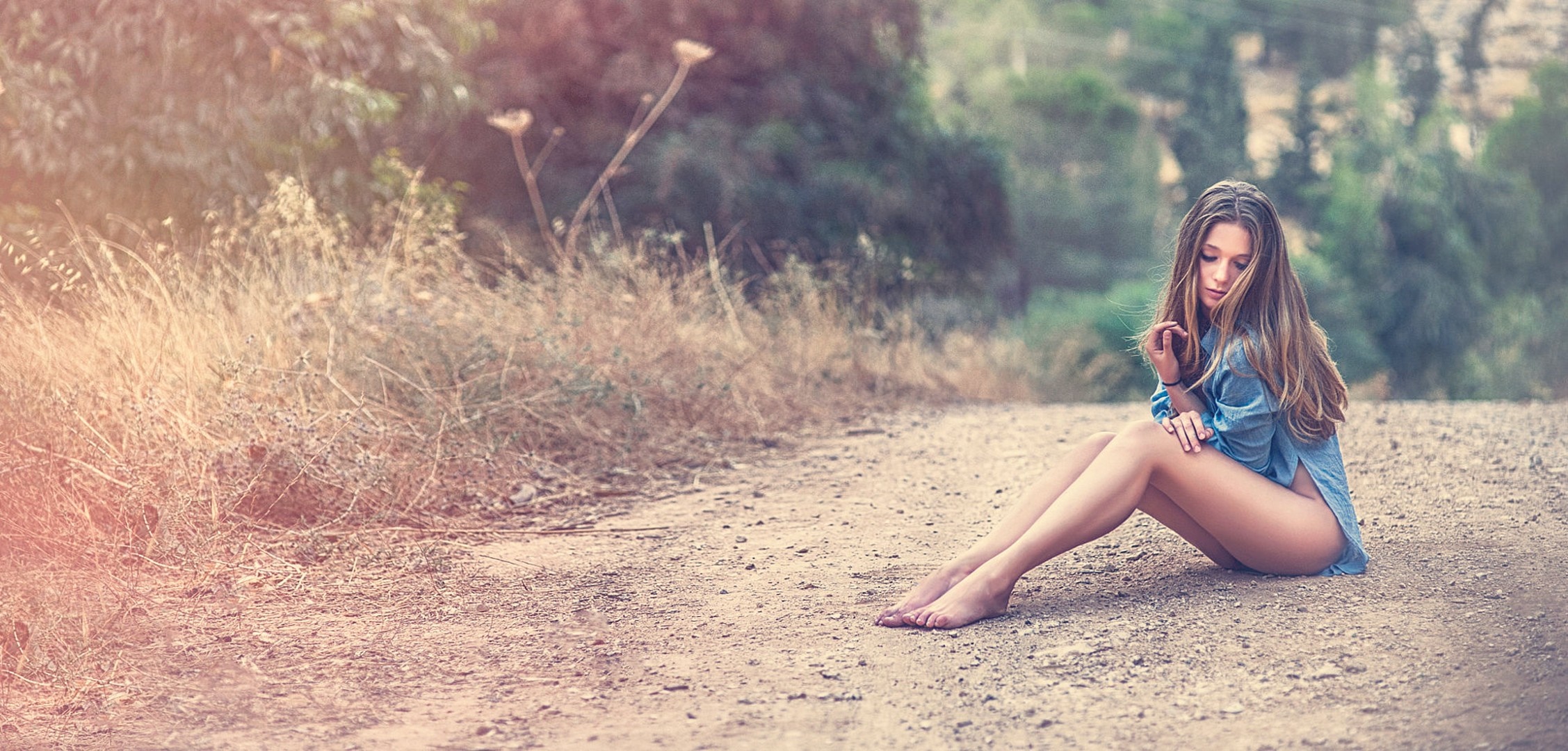 Woman with long hair sitting on a dirt road HD Wallpaper
