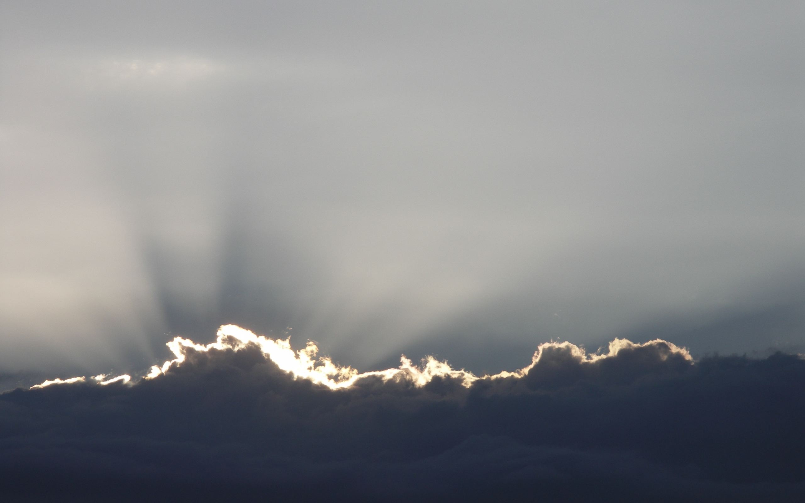 Sunlight beams through dark clouds at the horizon HD Wallpaper
