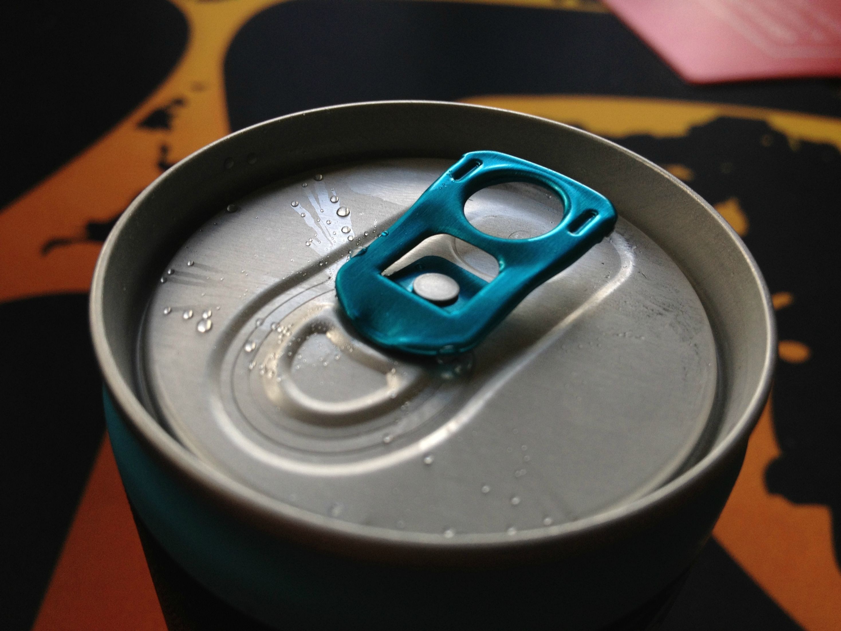 Close-up of a blue tab on a wet aluminum can HD Wallpaper