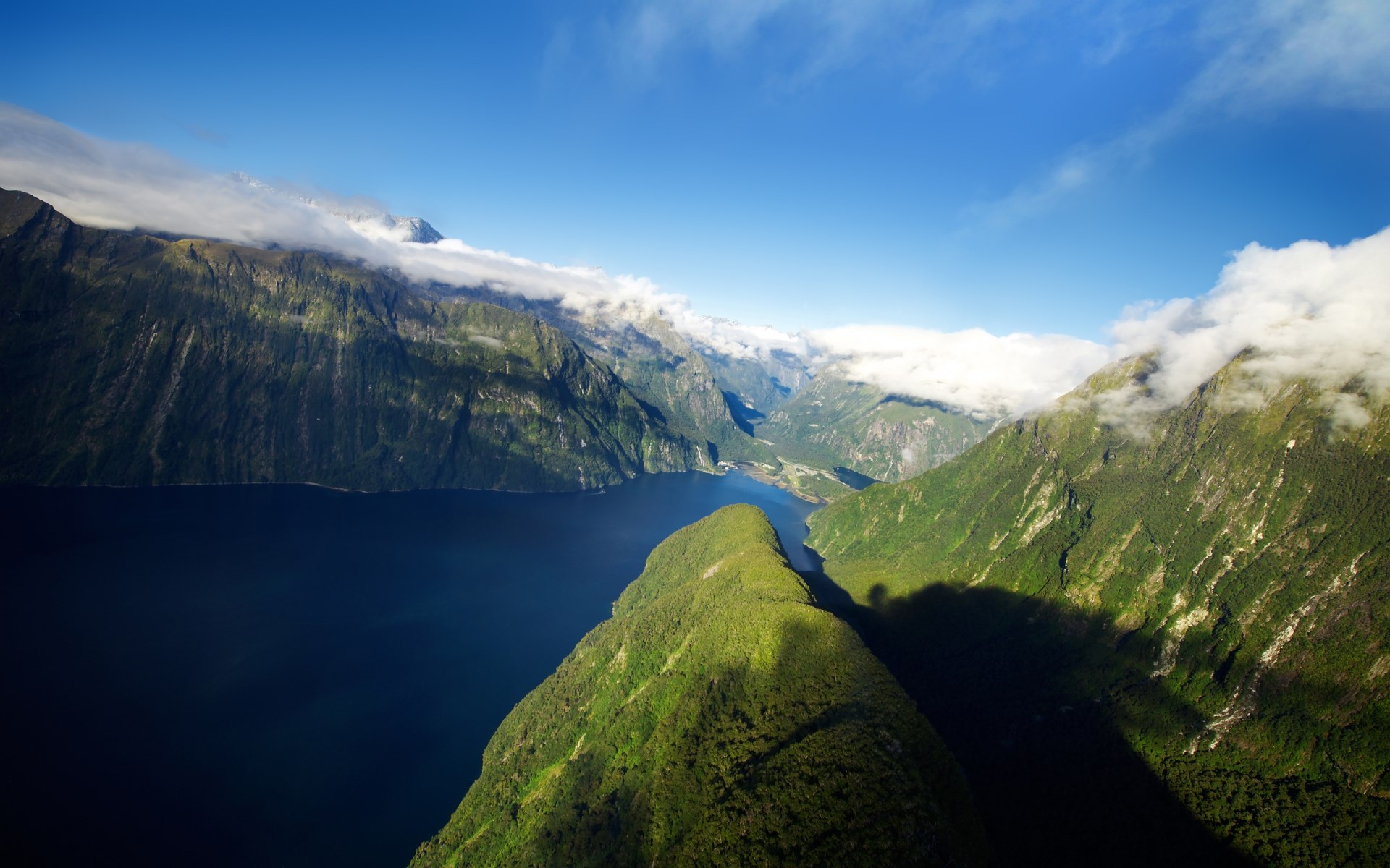 Aerial view of a deep blue fjord surrounded by green mountains HD Wallpaper