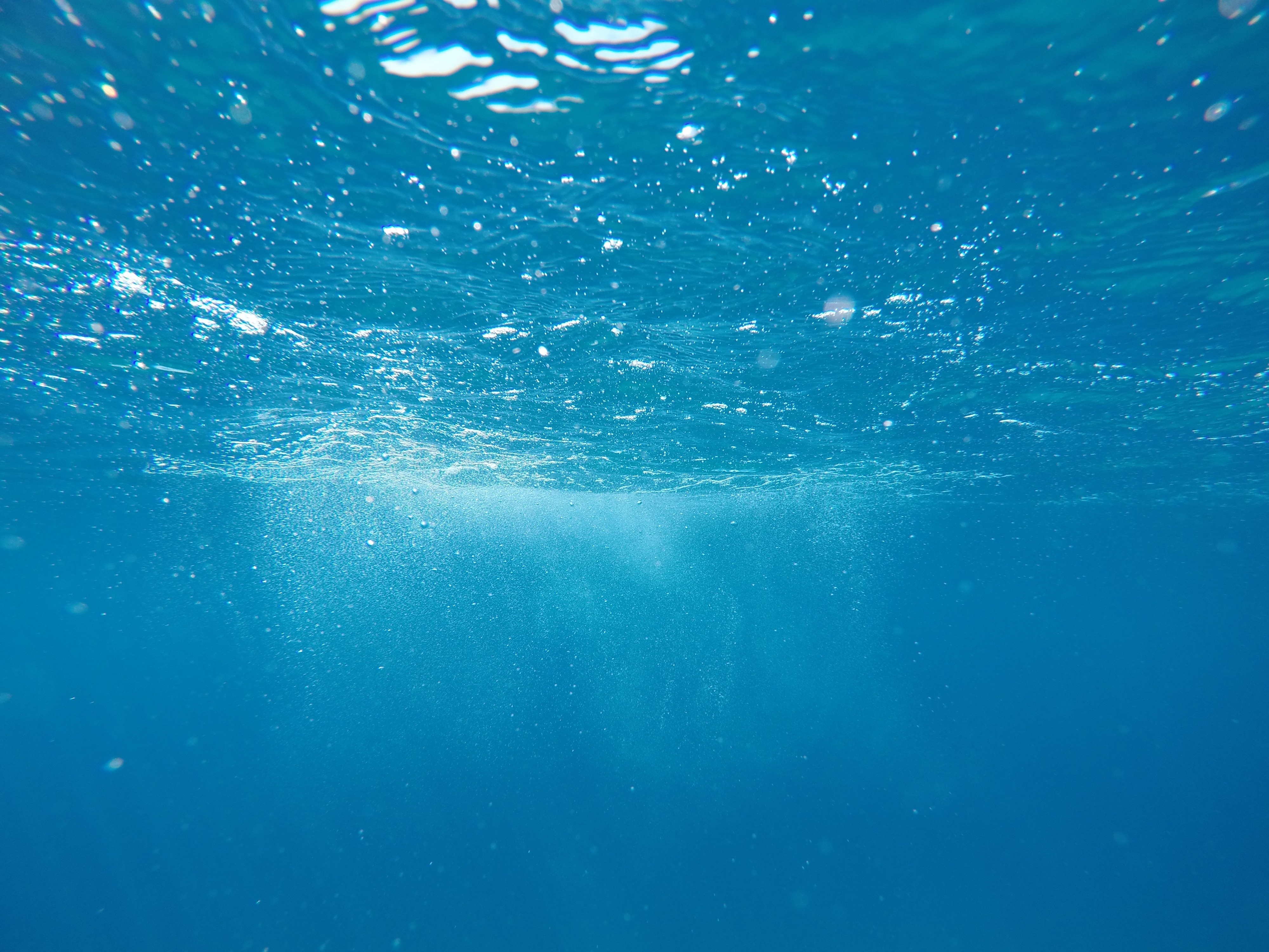 Underwater view of the ocean with sun rays and bubbles HD Wallpaper