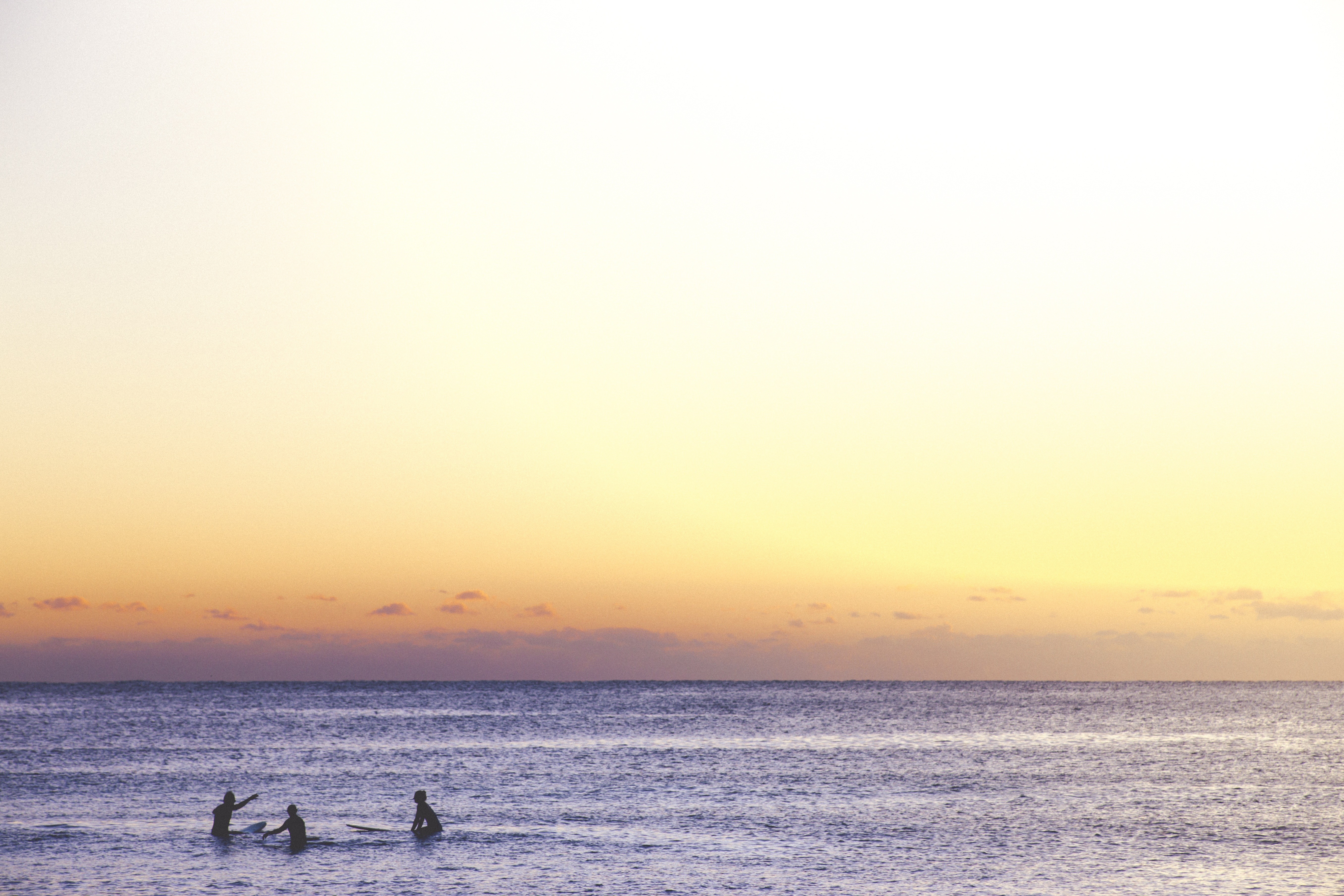 Surfers in the ocean at sunset HD Wallpaper