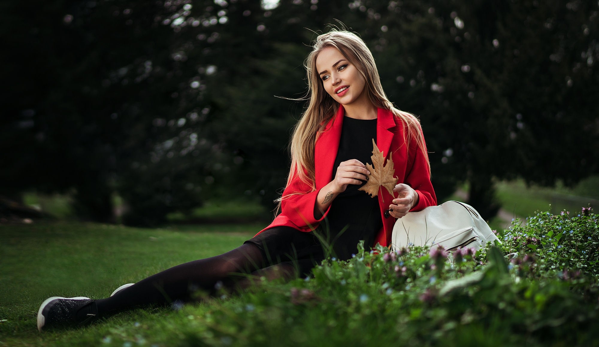 Woman in red jacket holding a leaf in a park HD Wallpaper