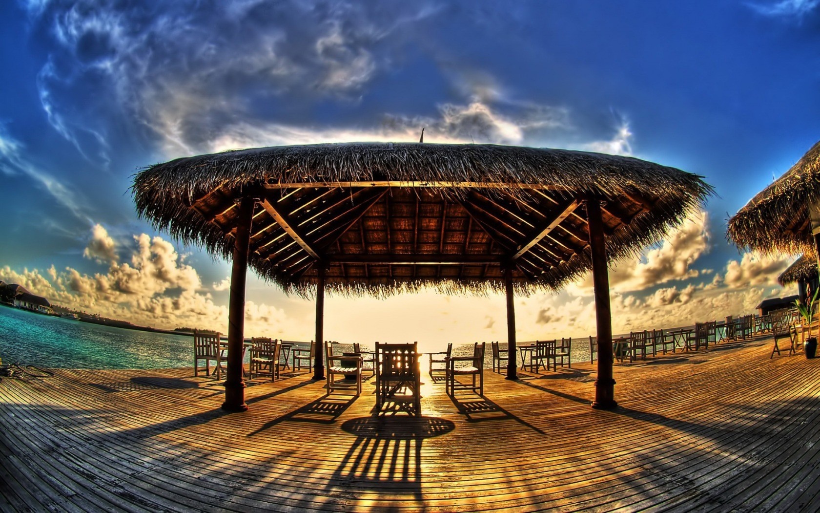 Beachside pavilion with chairs at sunset HD Wallpaper