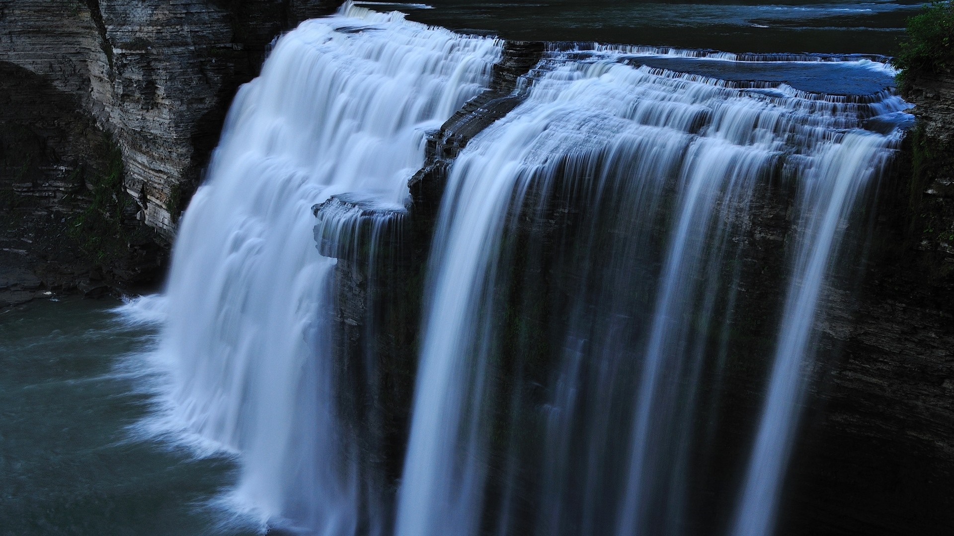Waterfall cascading over rocky cliffs into a body of water HD Wallpaper